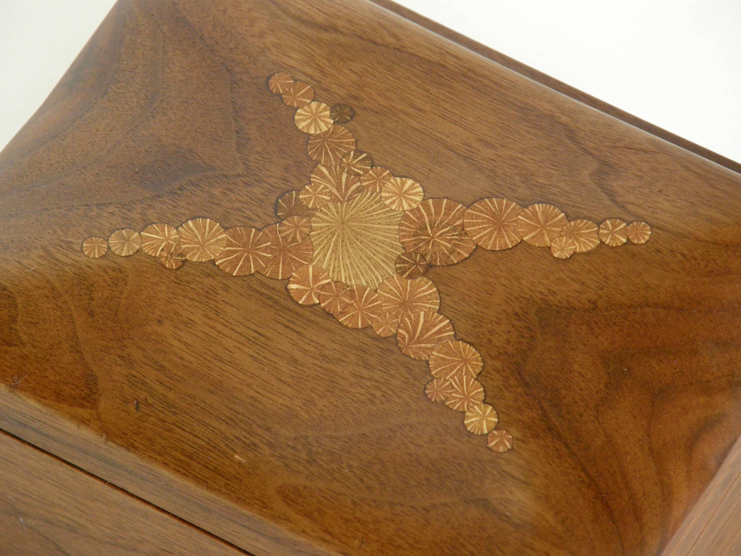 Carved walnut box by Roger Sloan with oak root cross sections inlaid on the undulating surface of the lid. The wooden hinge is beautifully made and has a strong and elegant stop running the length of its back that allows the lid to stay comfortably