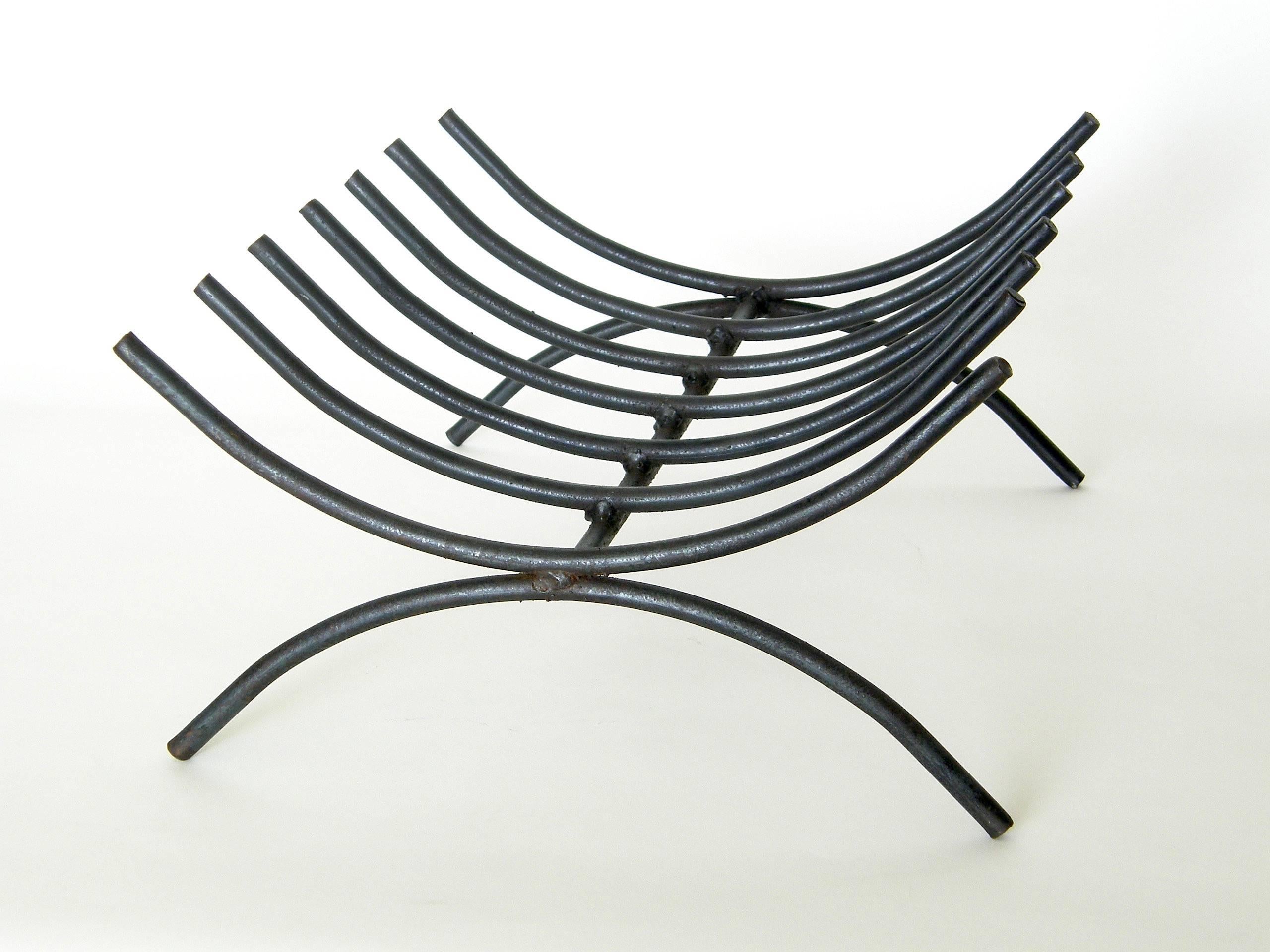 Mid-century modern, wrought iron log holder. This piece can be used either inside the fireplace for lit logs or outside the fireplace for storage of logs. It has clean, simple lines, and the design, rendered in iron rod, is reminiscent of a ribcage