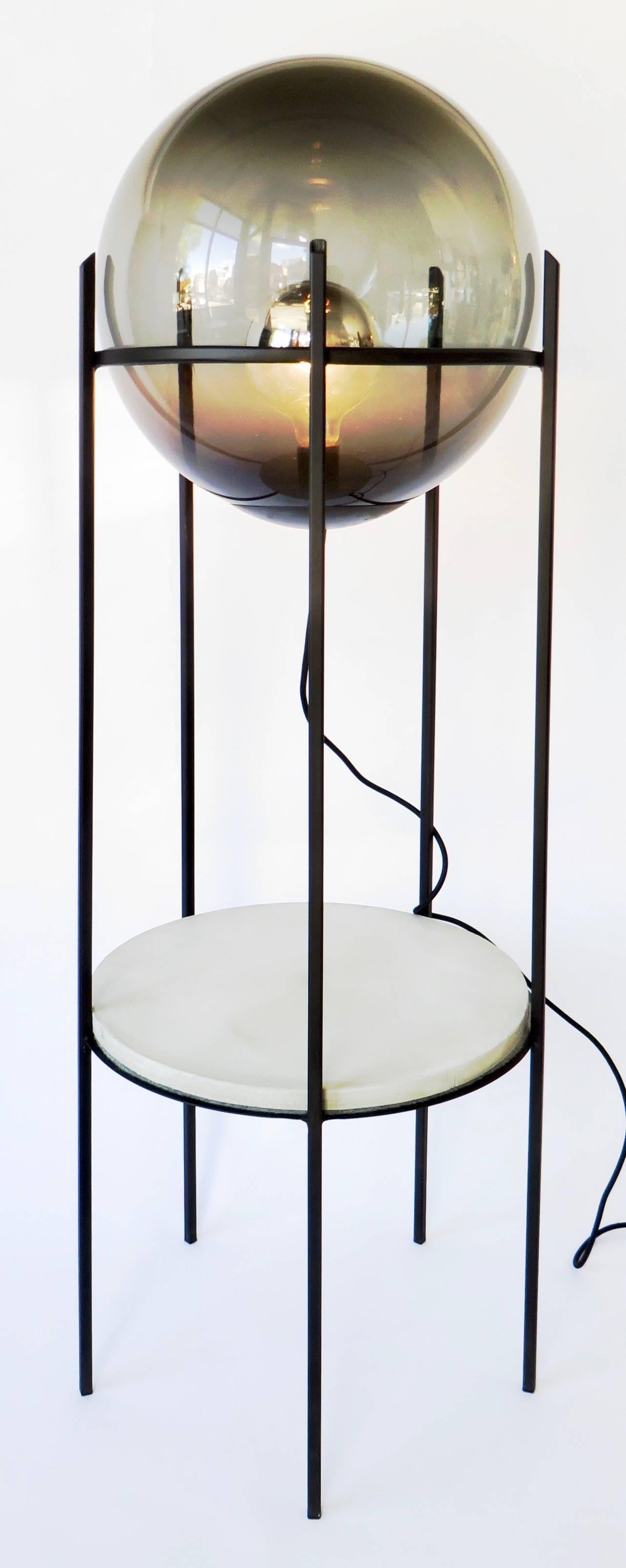 Two level floor lamp by contemporary artist and designer Hannah Vaughan.
Smoked handblown glass, cement plateau, and hand-wrought iron structure. 
 
Hannah Vaughan was born in Los Angeles, CA to a bookbinder and an artist. Hannah attended Oberlin