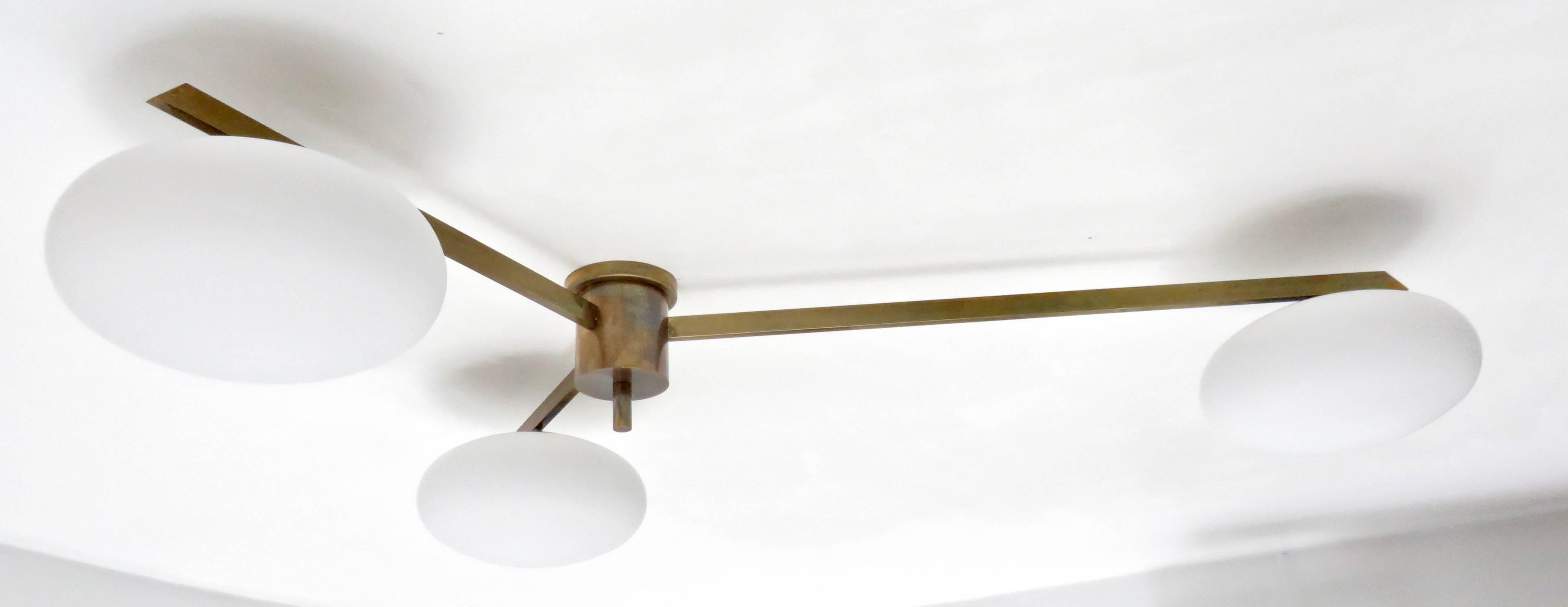 Three-arm ceiling or wall light sconce in the style of Angelo Lelli  for Arredoluce.
Original patina of brass structure with opaque glass shades.
Shown in detail shot with original sockets.
Signed with makes's mark on finial.
Overall measurement: