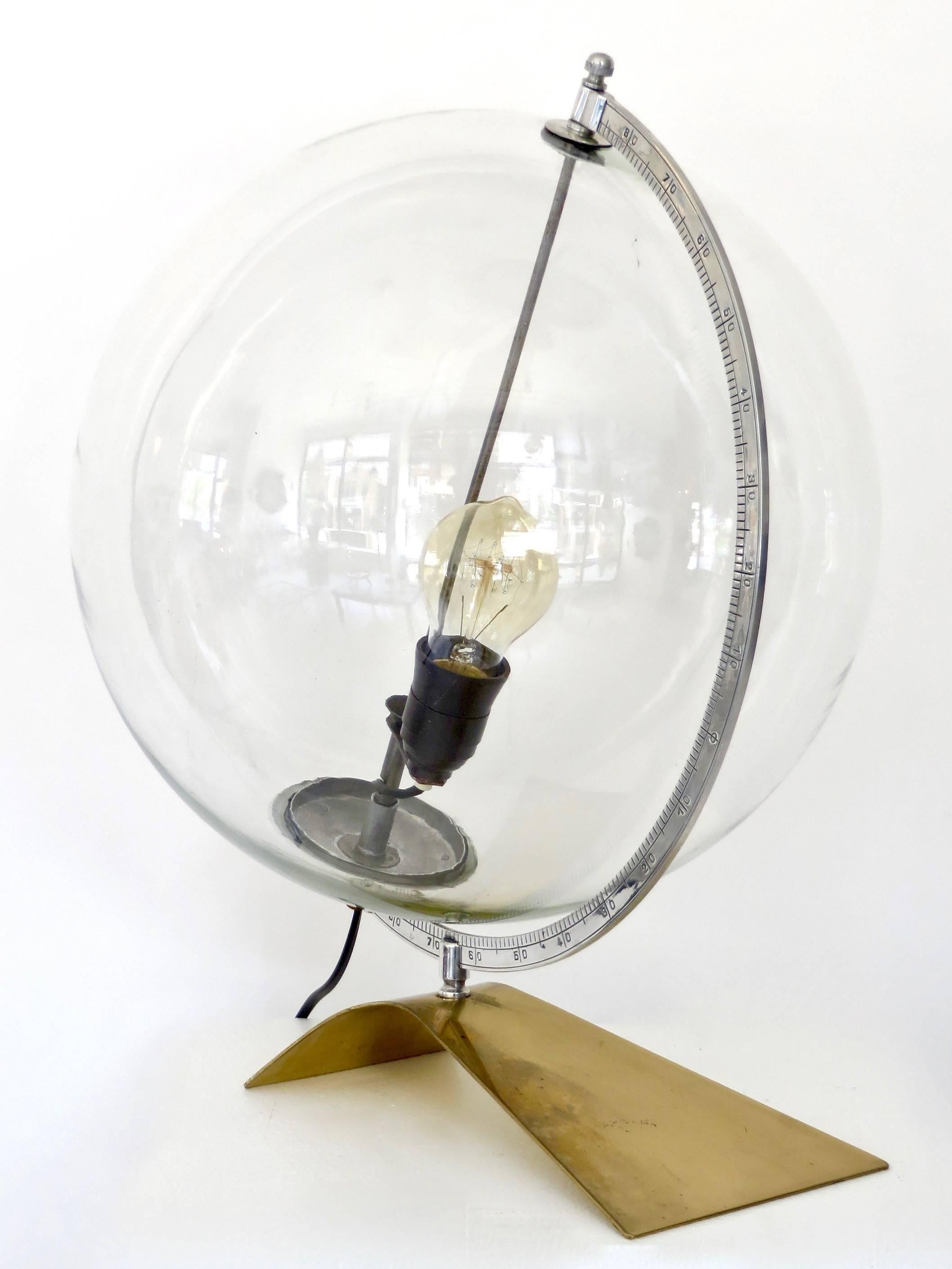 An Italian glass table lamp with brass base and steel armature forming a globe. The glass globe is mouth blown glass into a mold.
The steel armature has degree marks indicating decorative use as a globe
Overall size: 16" x12" x