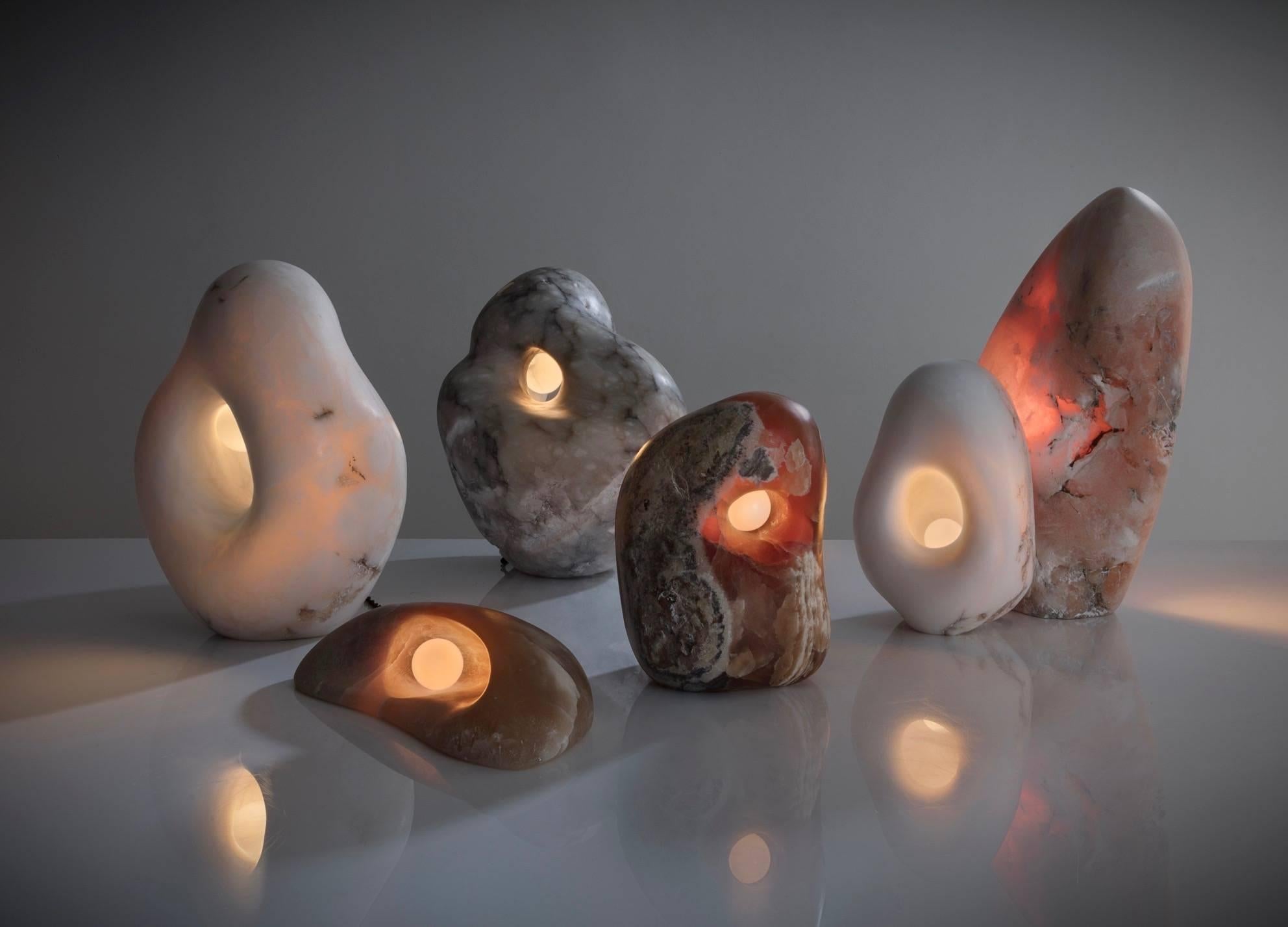A series of fertility form sculptural lamps in hand-carved translucent alabaster, agate, or calcite. Each piece is unique and each is hand carved and polished.
An ingenious round brass touch control on the back of each sculptural light is used to