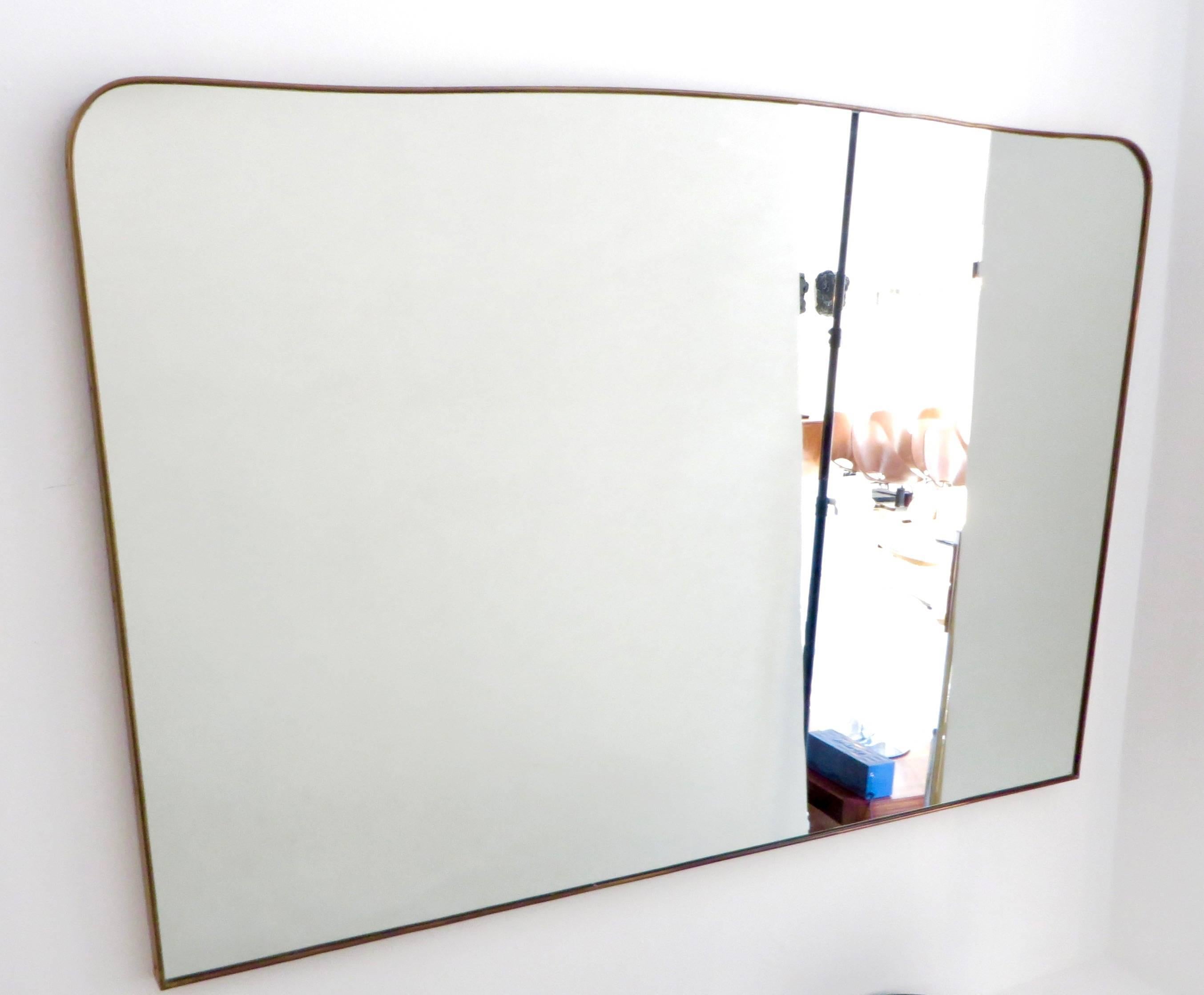 Monumental Italian brass mirror, circa 1940. A soft undulating top edge, with rounded corners and a slight taper in, on the sides. Frame is 1.5