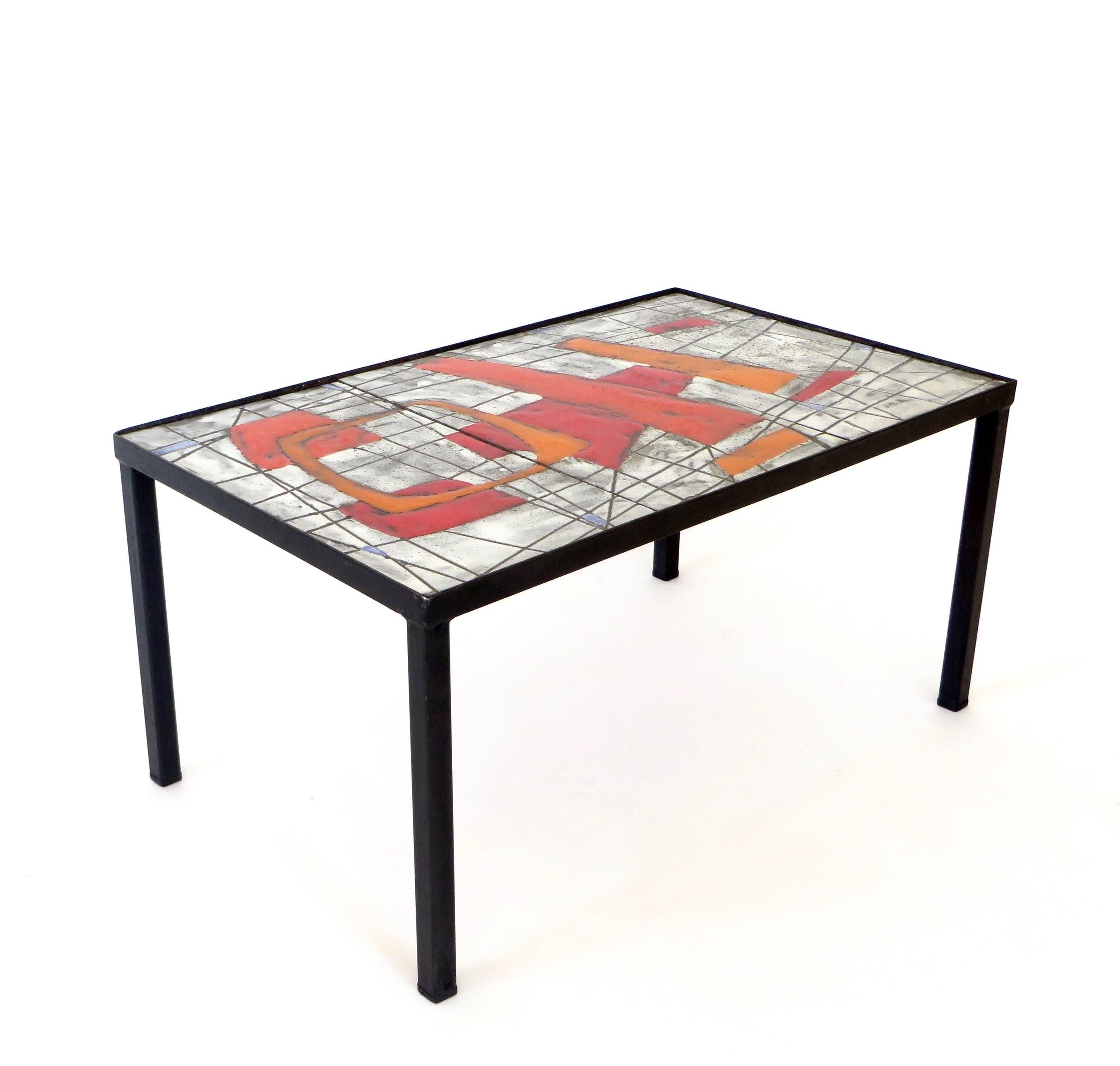 A boldly colorful and graphic ceramic tile glazed top with black metal leg structure, circa 1960, France. Colors of orange, red, grey, black and touches of blue by Jean and Robert Cloutier. 
Documentation: Les Freres Cloutier written by Patrick