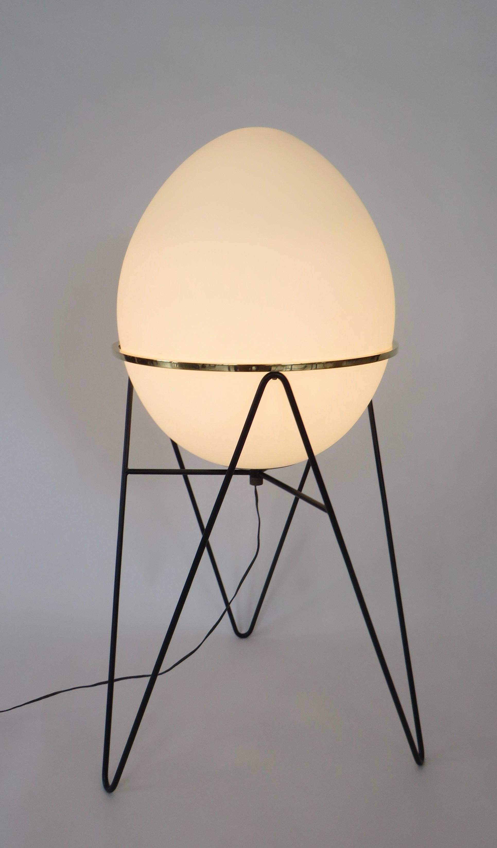 A very Minimalist pair of Stilnovo egg opaline glass floor lamps on a black lacquered metal frame with round brass frame holder the glass.
Brass hardware and on/off switch, enameled black iron base with brushed opaline glass.
Original cords. Each