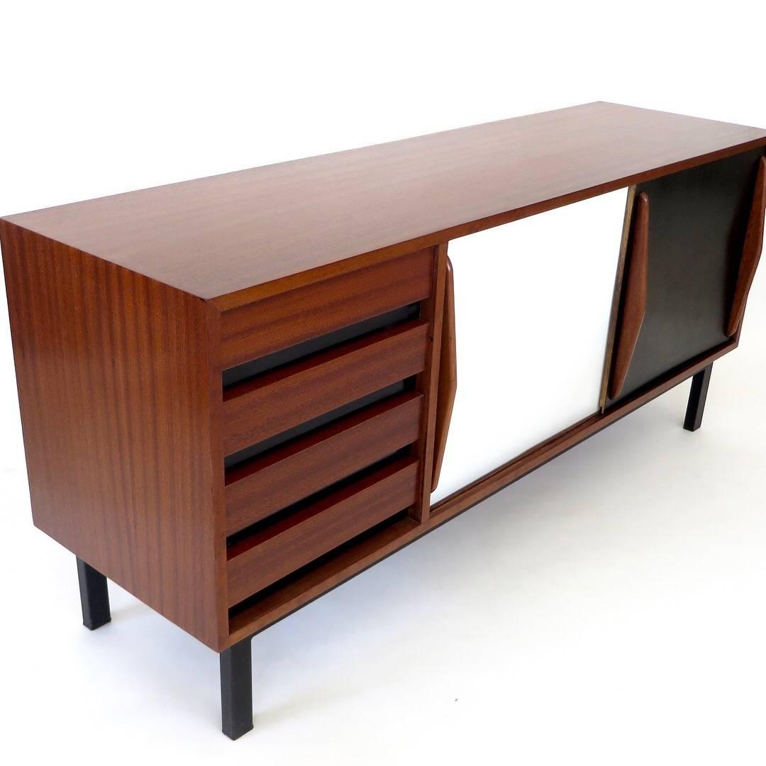 This Cansado four-drawer and sliding door sideboard was designed by Charlotte Perriand circa 1950 in the city of the same name in Mauritania. 
It was manufactured in France and editions by Steph Simon, her longtime dealer. 
It has a steel base,