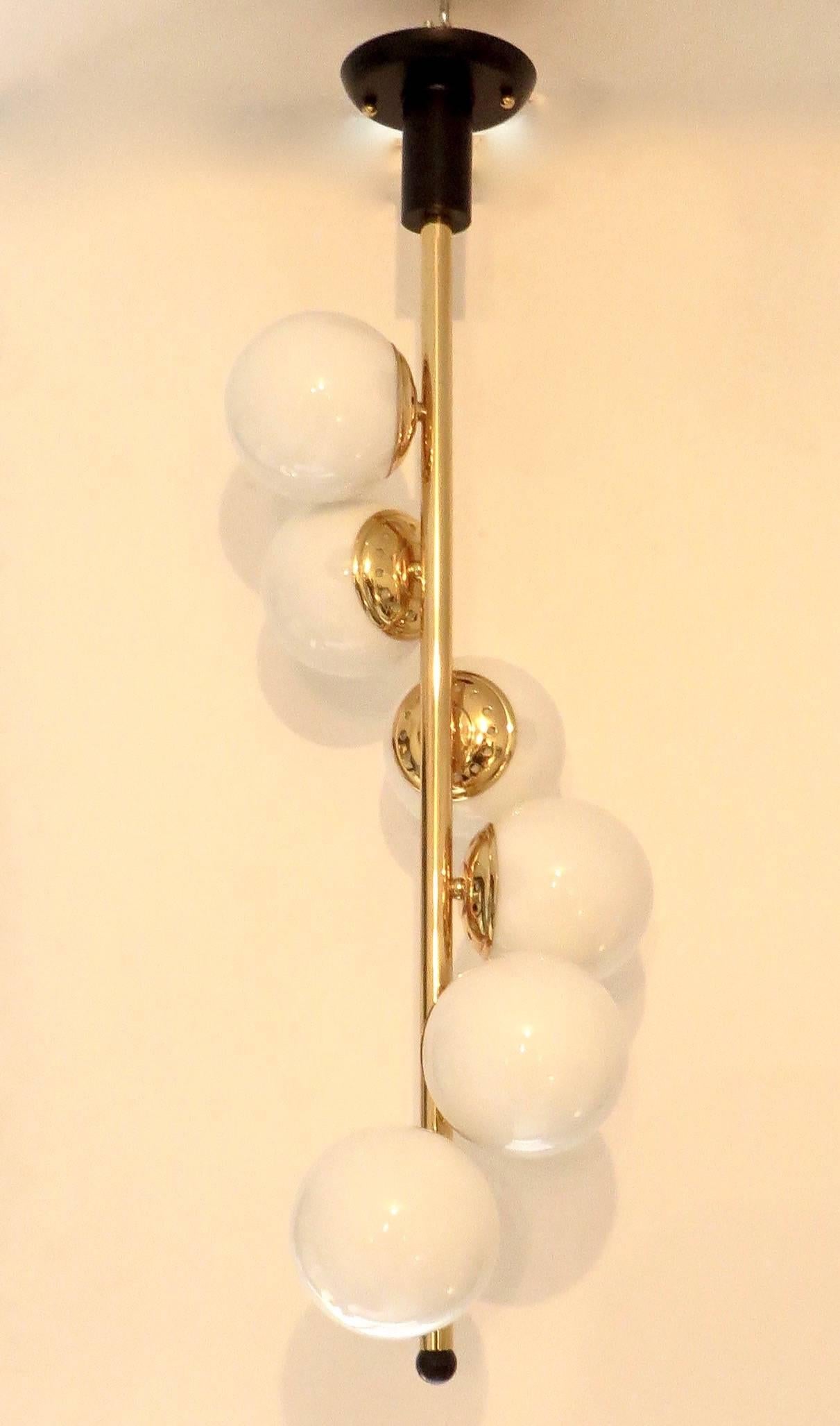 An iconic Italian chandelier by Stilnovo with the glass globes descending in a pattern down the central brass pole. 
Restored and rewired. 
All original glass globes.
Overall dimension from the top of the ceiling cap to the bottom of the black