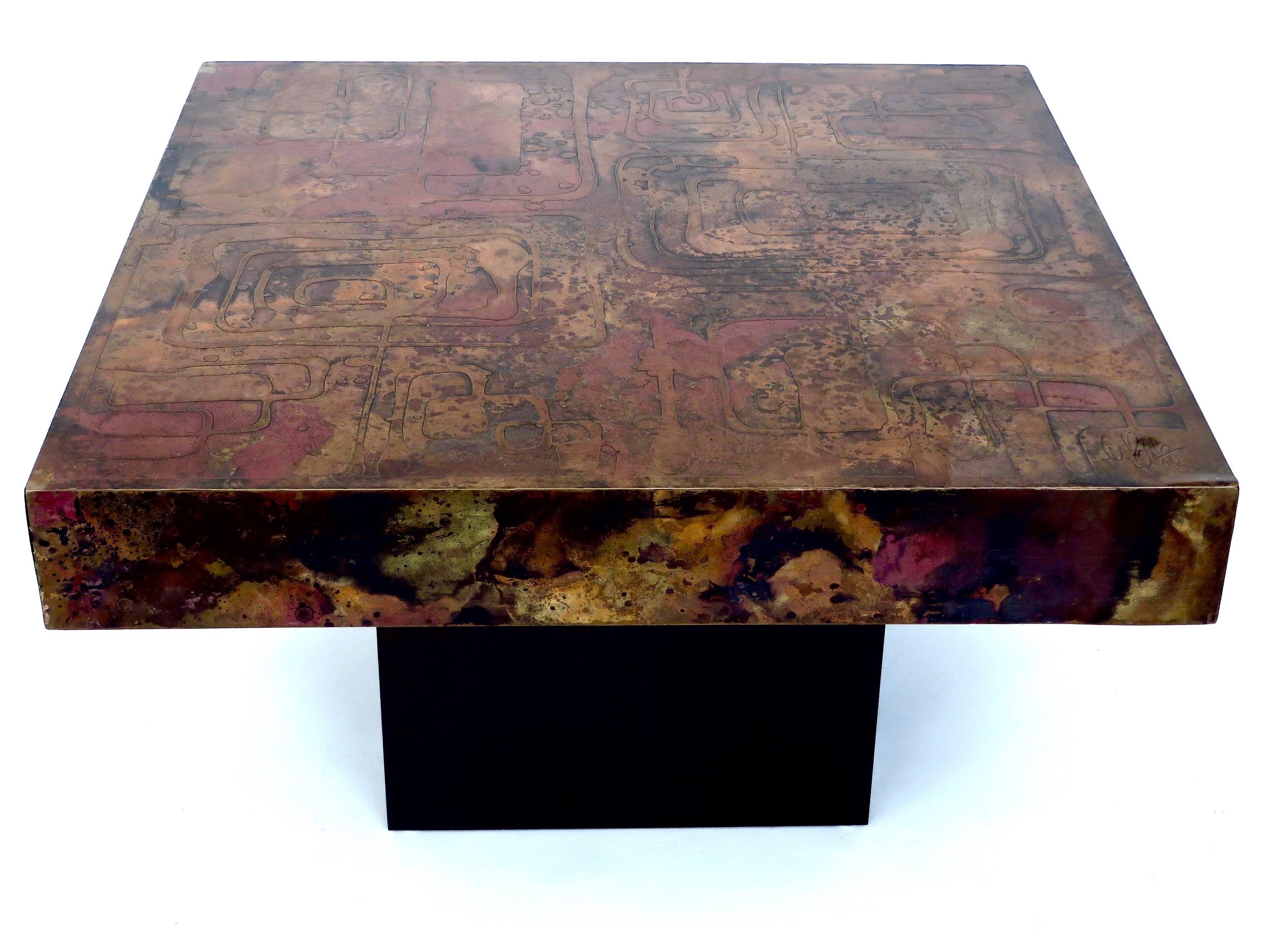 A large etched abstract scene Belgian signed coffee table on a black wood base. 
The undulating abstract design in copper and brass and varying shades of darkened copper, black and red patina, with raised areas. 
Smooth patinated copper sides, 4.5