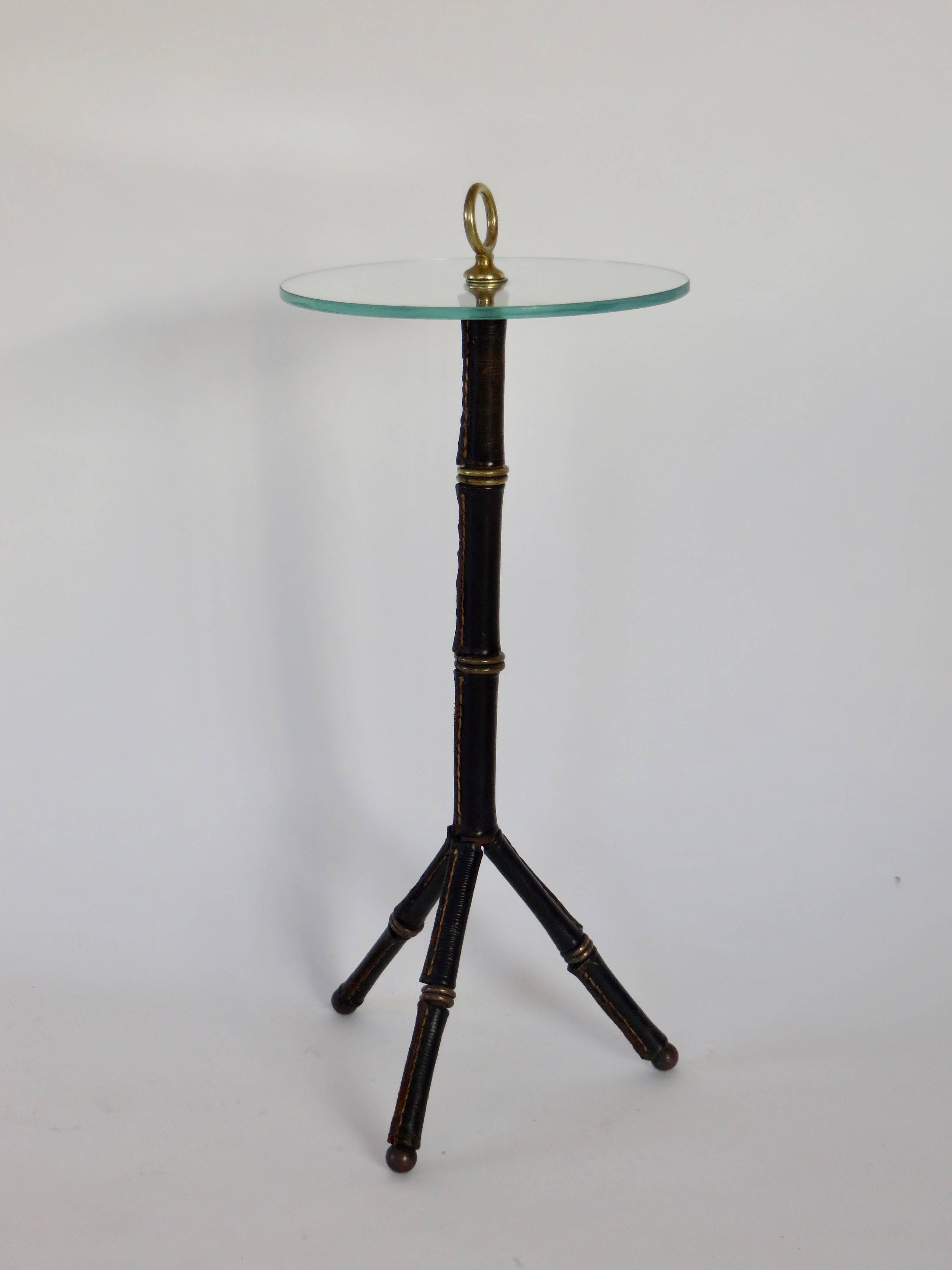This standing tripod vide poche by Jacques Adnet is in black leather with iconic brass details on brass ball feet. 
France, circa 1940.
It could be used as an a drink table. 
Excellent condition with no repairs to the leather. The glass has