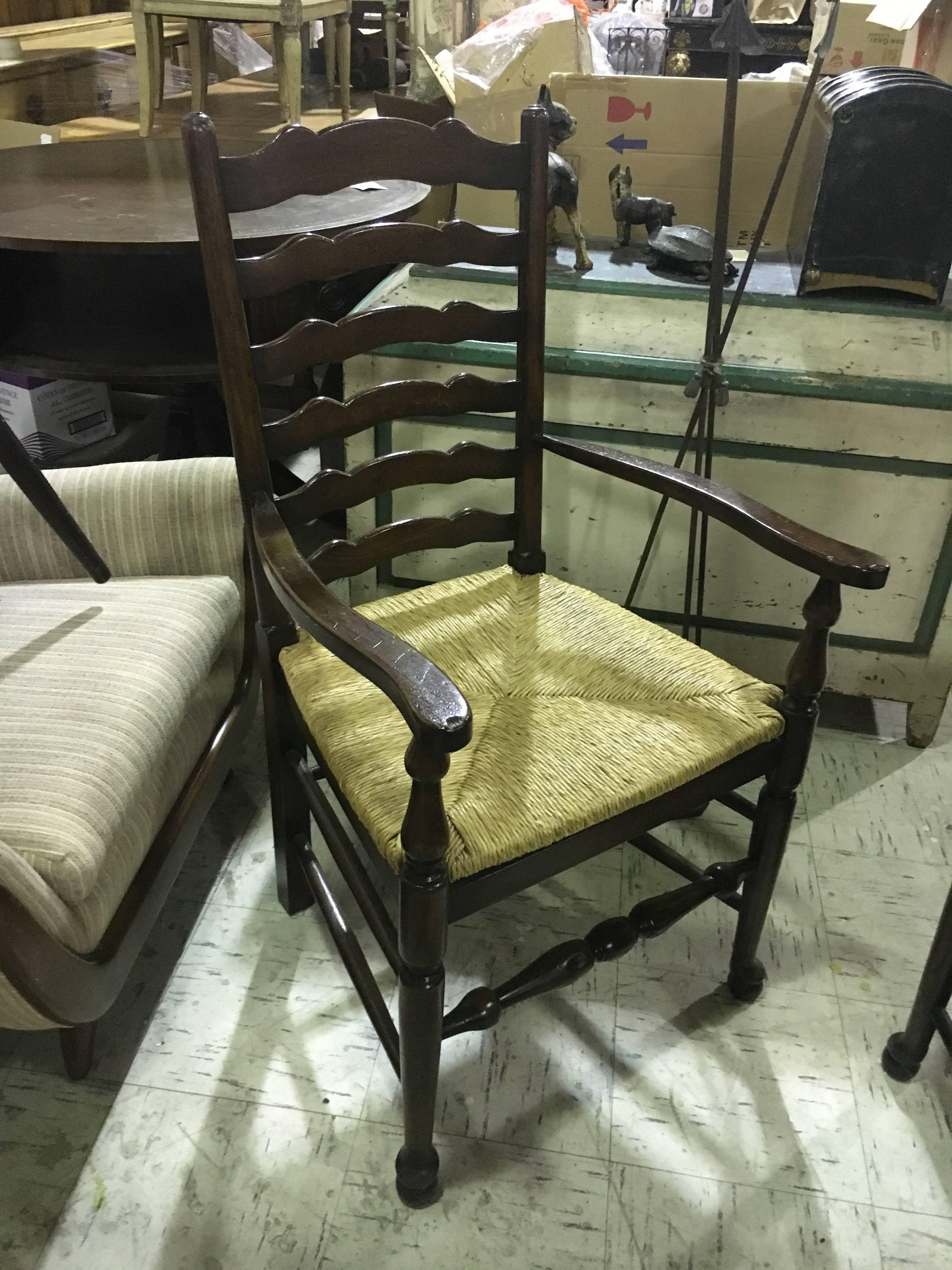 Four English oak ladder back armchairs or two pairs. Lovely deep rich color. Very comfortable. Rush seat in very sturdy good condition. Priced per chair.