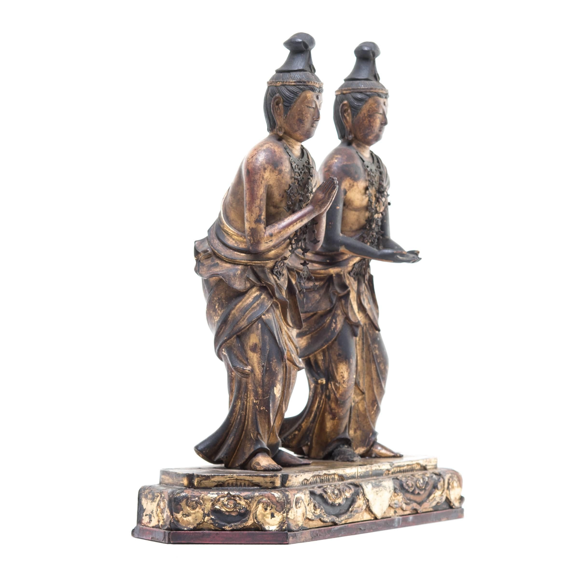 It is unusual to see two majestic carved Buddha figures mounted together. Each of the pair is in a different mudra position: One offering and the other blessing. Both are intricately carved with serene expressions, flowing robes, elaborate necklaces