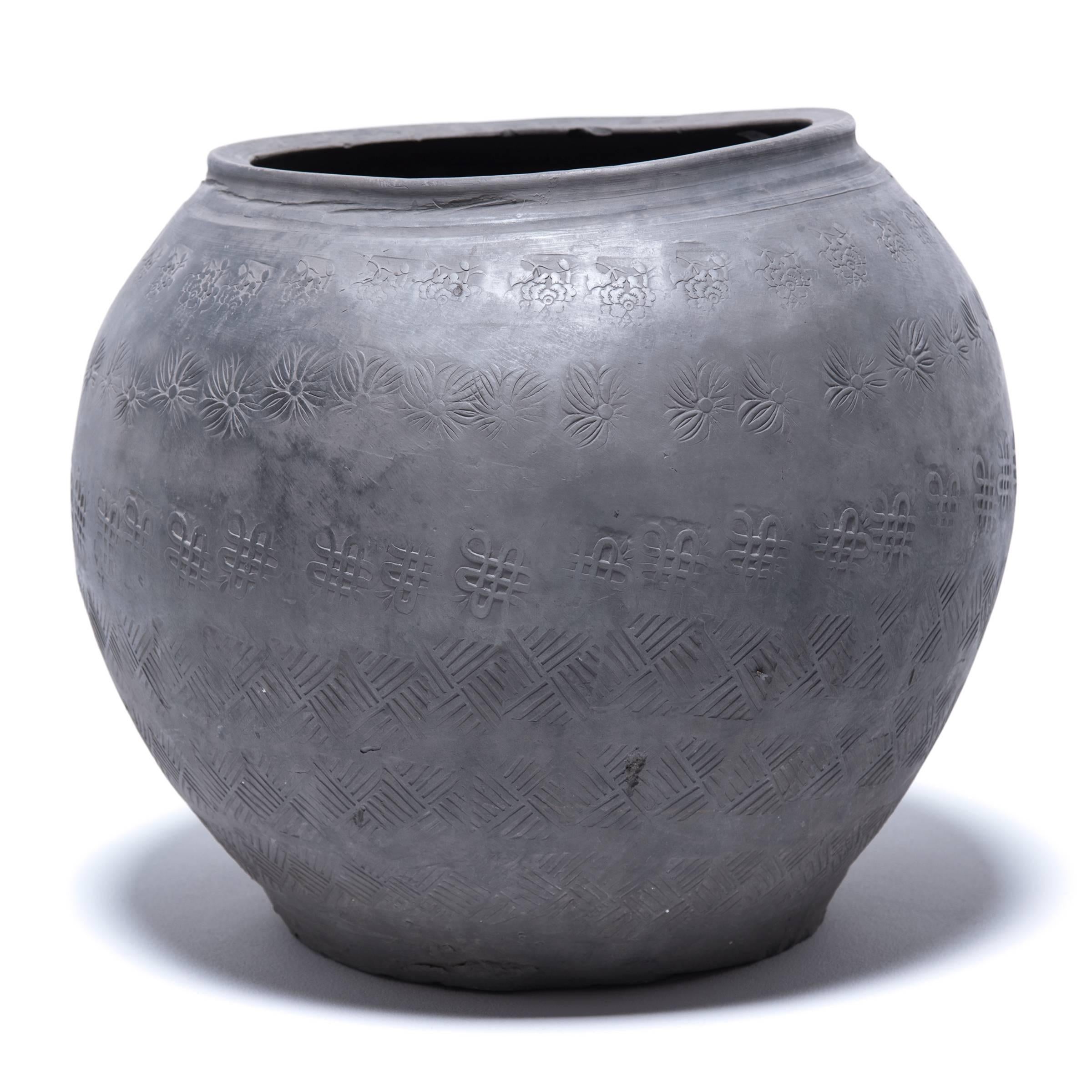 Over a century ago, a gifted potter from northern China crafted this organic feeling clay jar out of rich, dark river clay mined from the river basins of Asia. The surface is stamped with auspicious symbols: The Tibetan Buddhist endless knot, and
