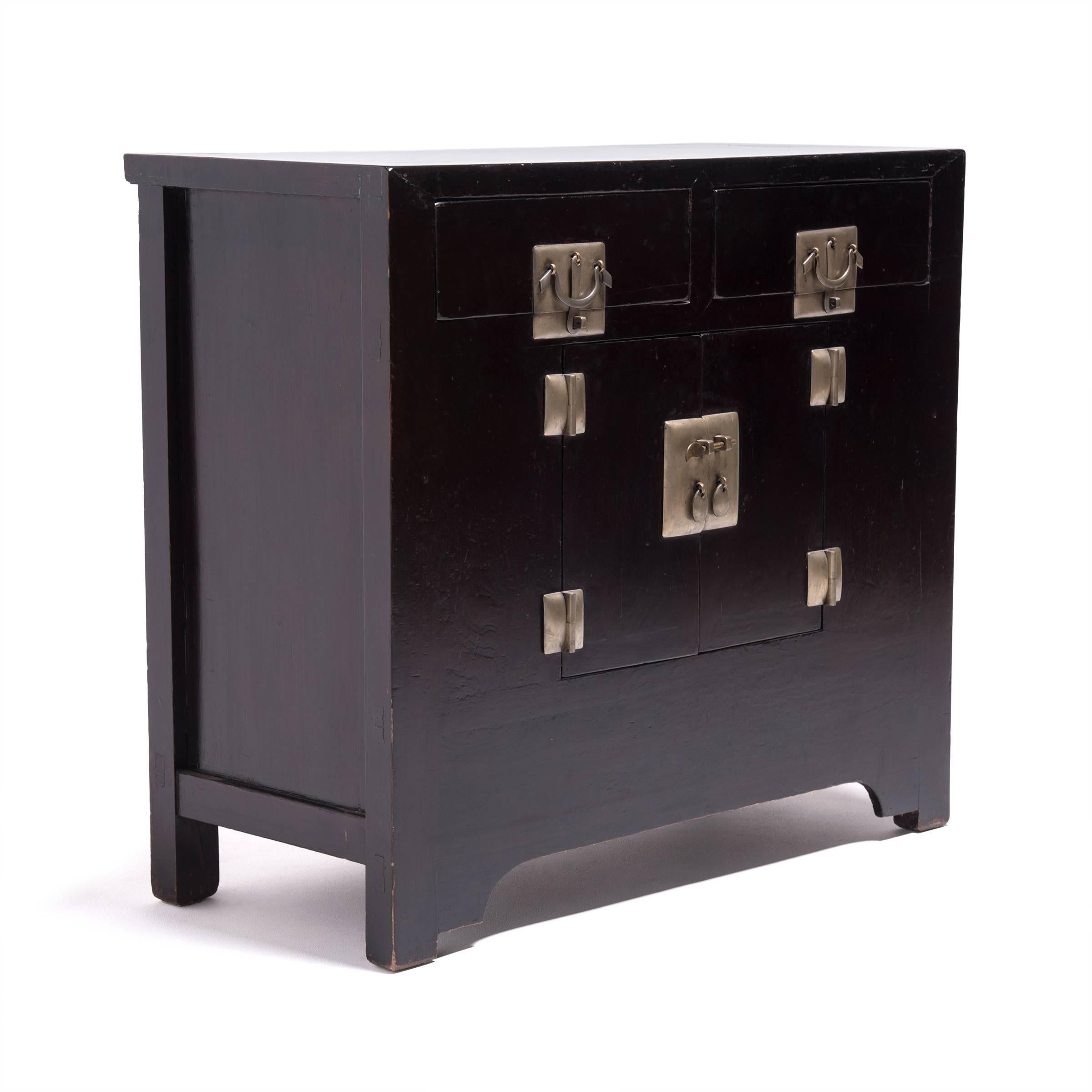 Made of northern elmwood, this stunning mid-19th century cabinet is distinguished by its beautifully aged lacquer finish and unique cushion hardware. To achieve its deep black color and lustrous sheen, artisans applied as many as 30 coats of lacquer