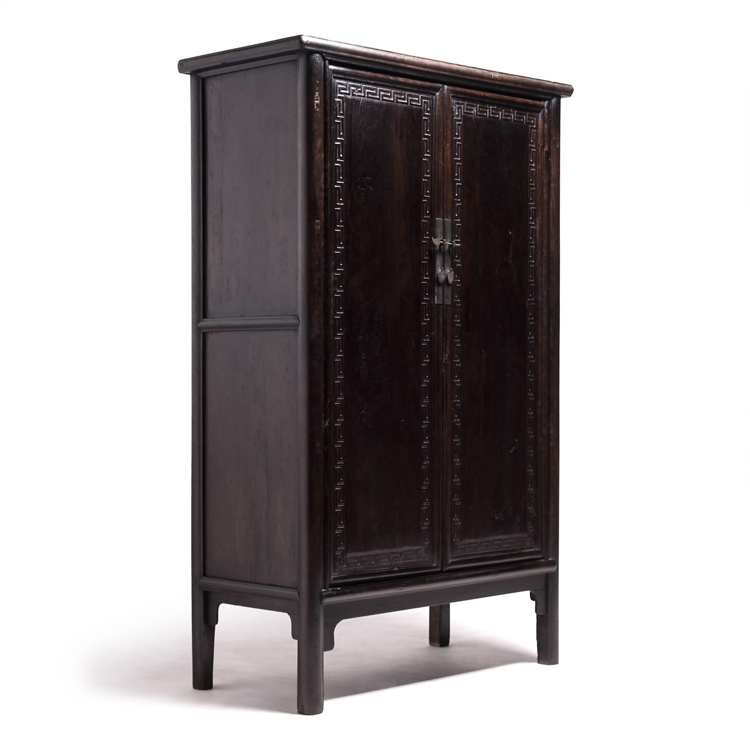 Unusual to Chinese furniture, a Greek key-like design, crisply rendered in walnut, outlines the doors of this exceptional cabinet. The motif, however rare, emphasizes symmetry, an important Chinese concept both symbolically and aesthetically.