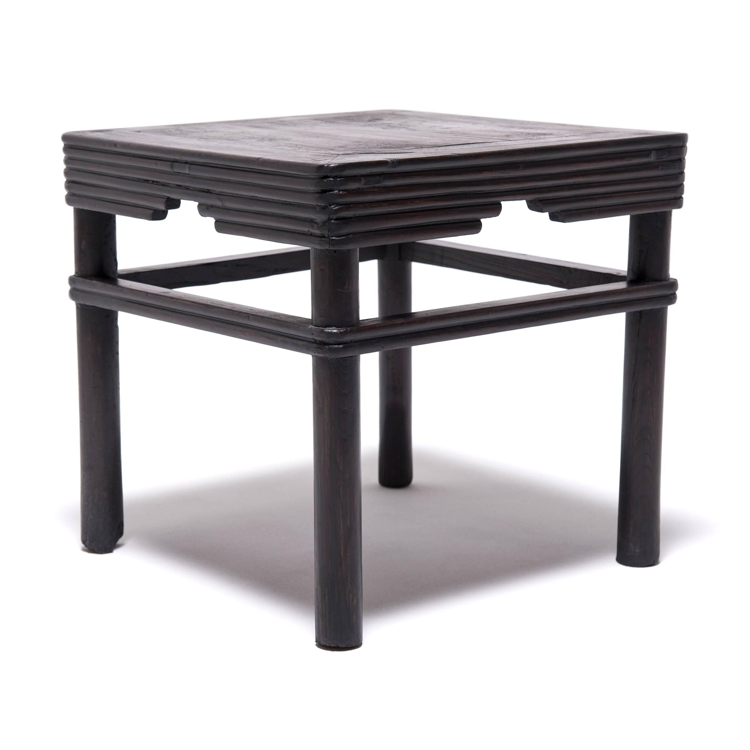 Paying tribute to the humble virtues of bamboo, ribbed woodwork wraps the legs and creates a stepped apron for this square stools known as a feng deng. Expertly crafted from elm foraged from the forests of northern China, this stool was made in the