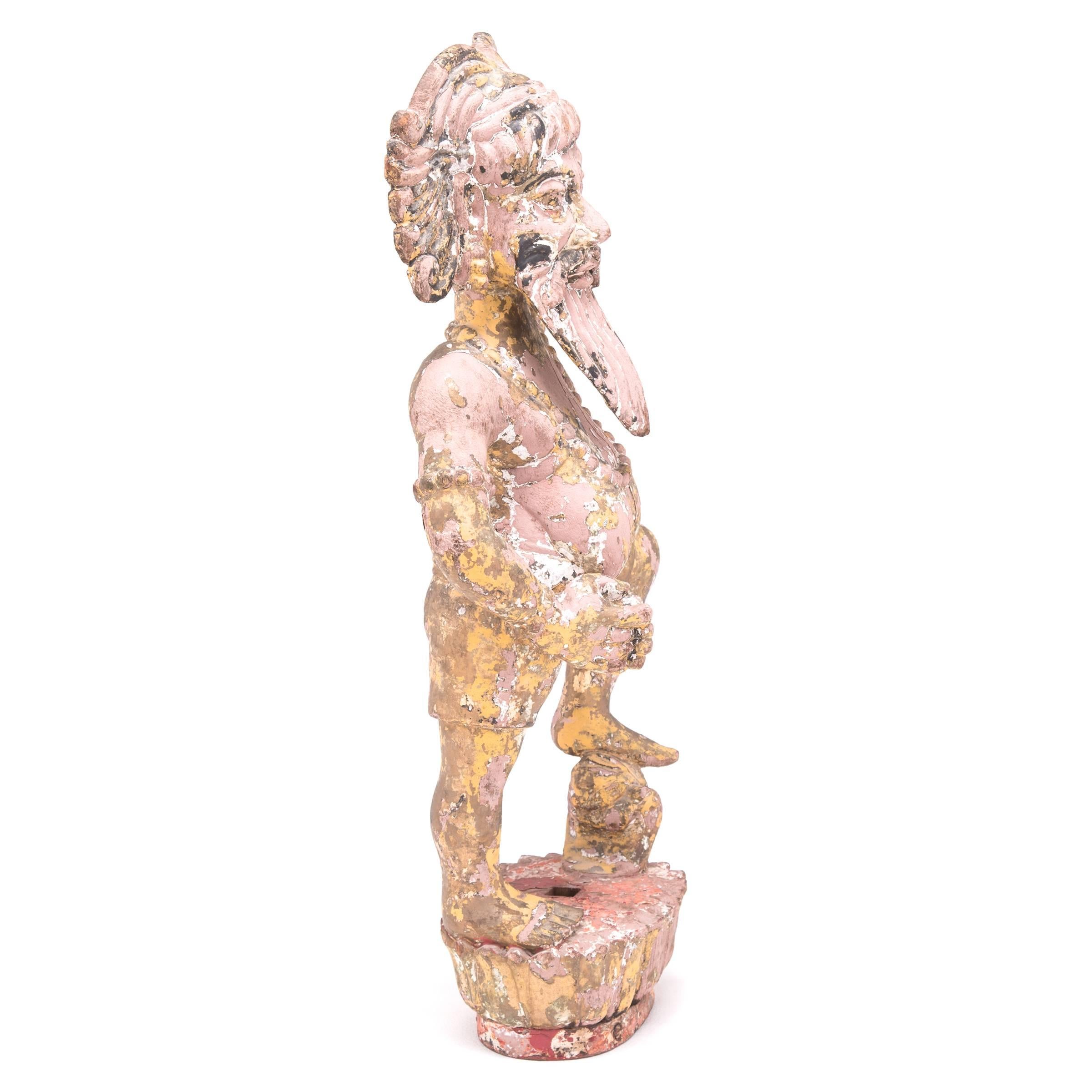 Likely representing a divinity figure, this expressive wooden figure possesses both a sense of whimsy and potent energy. Remnants of pigment suggest that this sculpture was once accented with vivid color, further imbuing the figure with a powerful