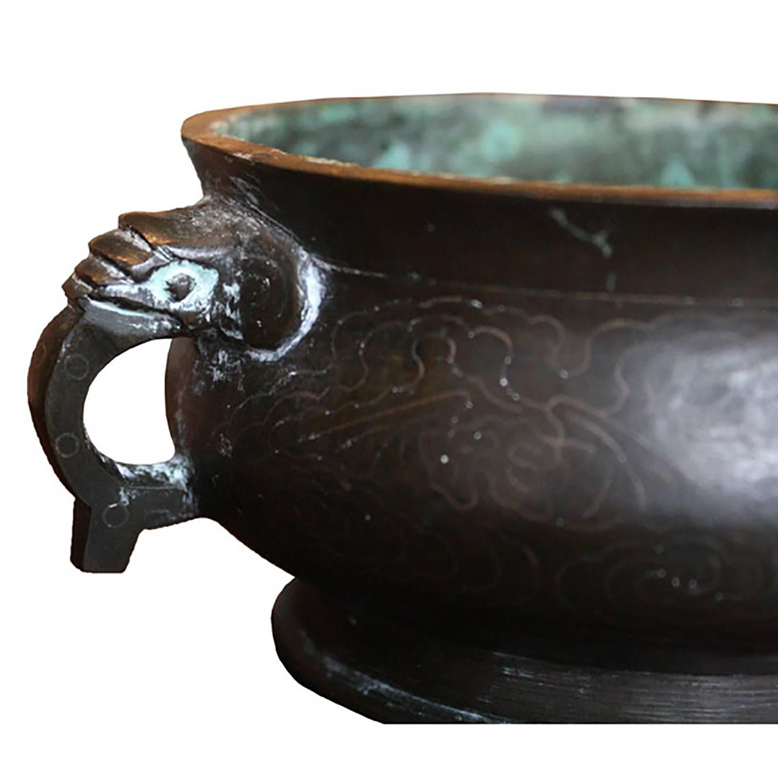 Delicately engraved with clouds and cranes, this 18th century bronze censer once held incense, lit for prayer or meditation. Clouds represent heaven and cranes, thought to live very long lives, represent longevity. Its handles are auspicious