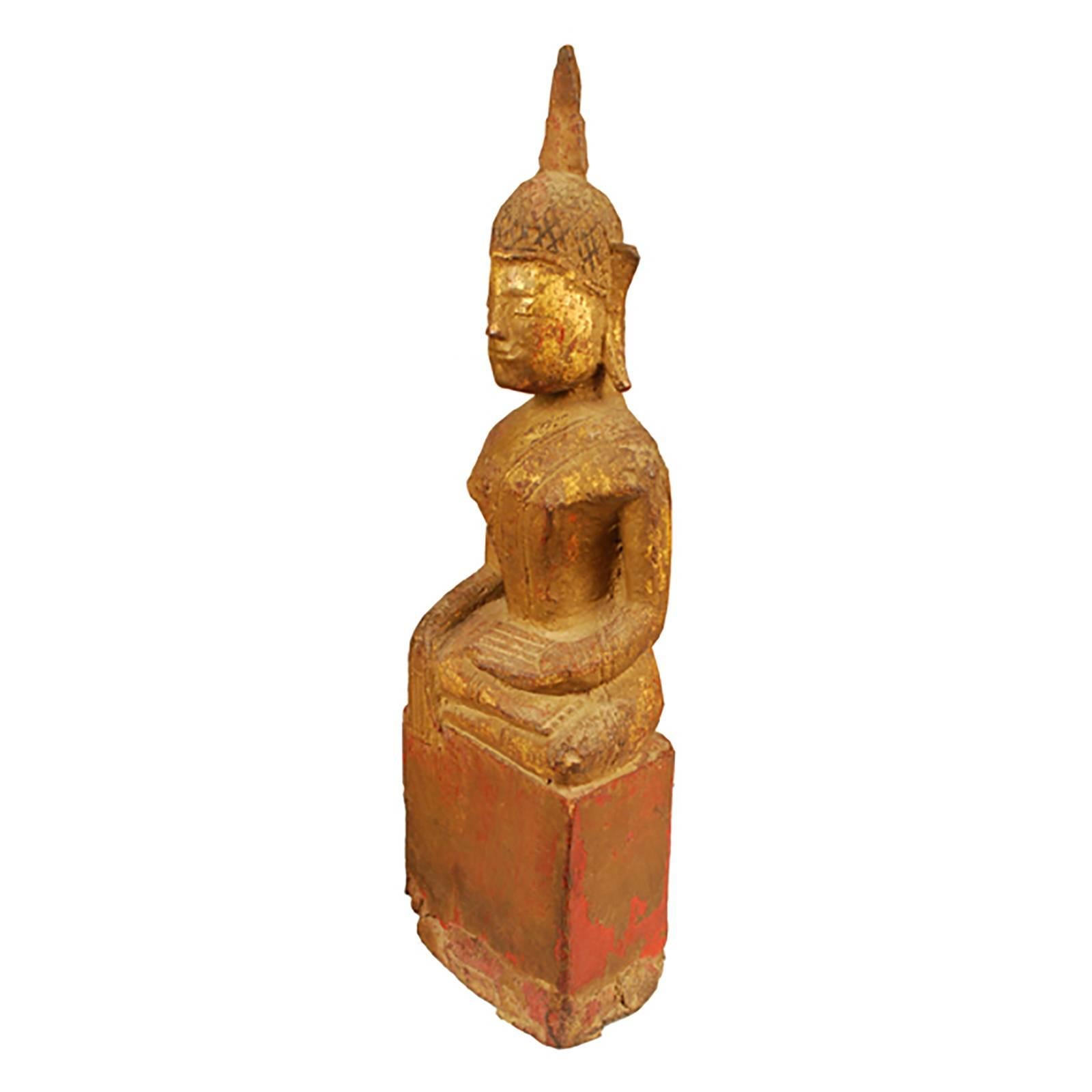 This simple, finely rendered wooden Buddha was hand-carved over a century ago in Thailand. The creator focused their intricate detailing on the head and face. While many similar Buddha sculptures involve finely wrought seats, this piece draws the