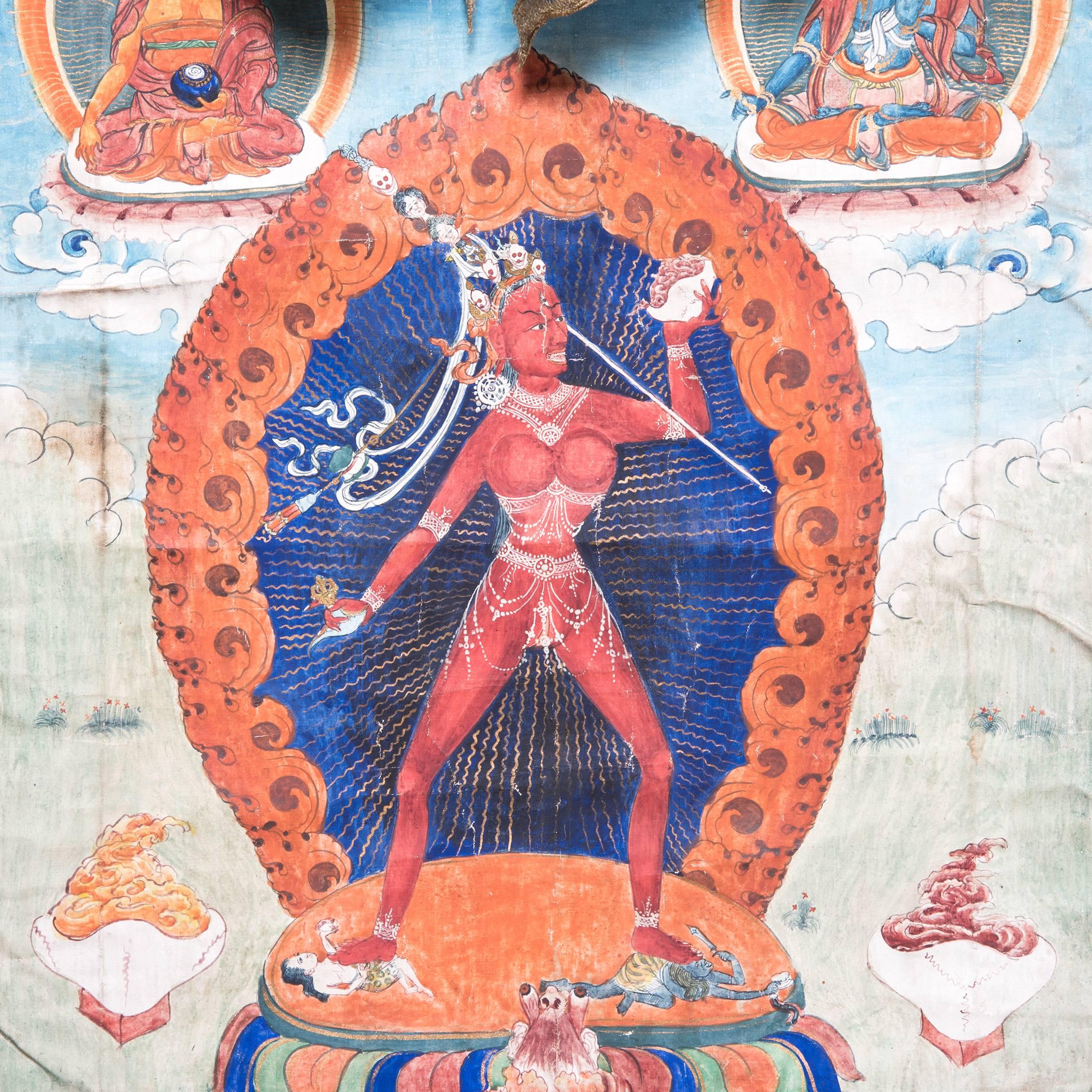 Tibetan Thangka, the deity depicted in the centre standing on two human figures before a mandala atop a lotus plinth, the left hand raised bearing a skull and the right hand holding a chopper, the naked body adorned with beaded jewelry and an
