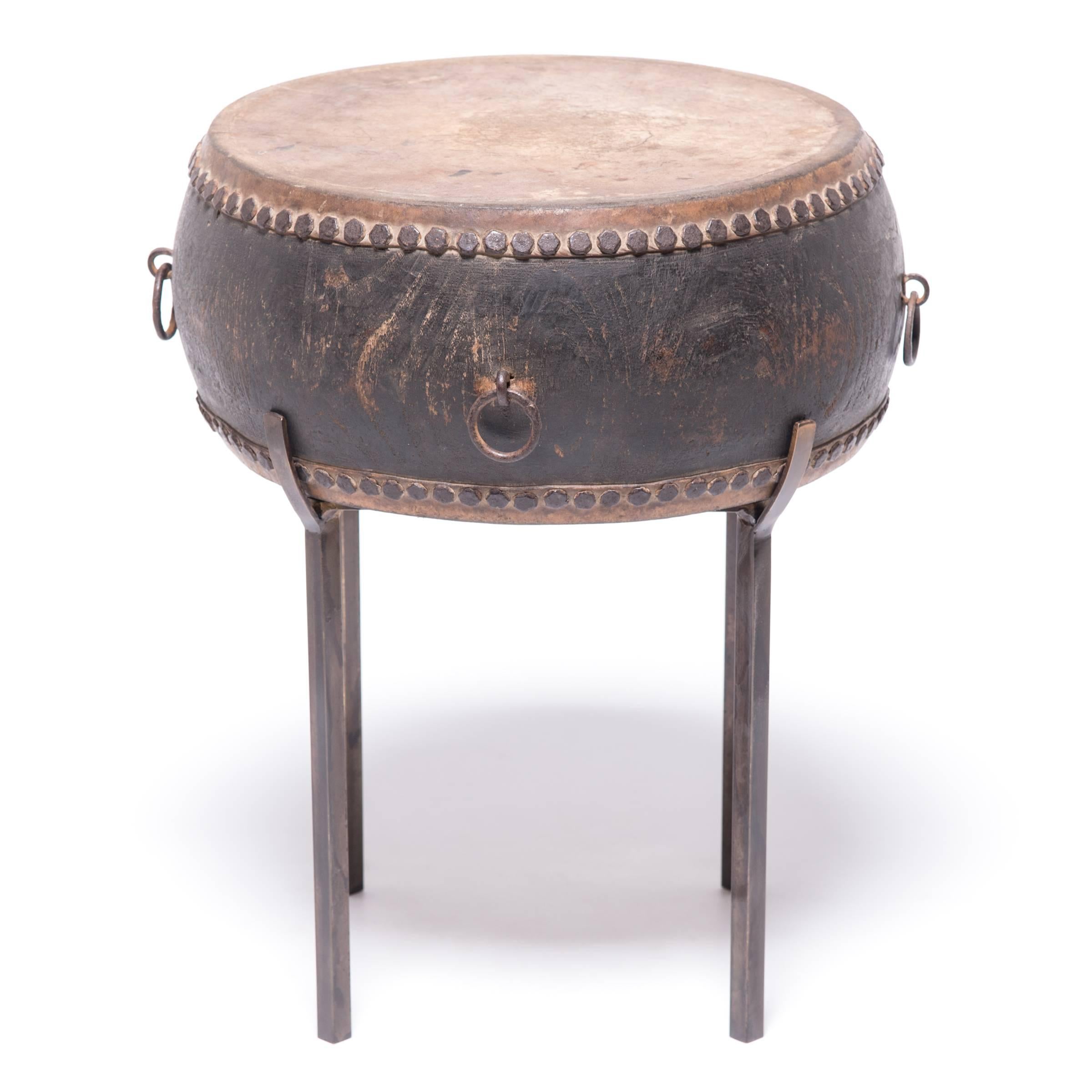 This late 19th-early 20th century wooden drum was made by hand in Beijing, China. The hide top and bottom is finished with handmade iron nailheads. This drum would have originally been used in a procession or possibly as part of a Peking opera