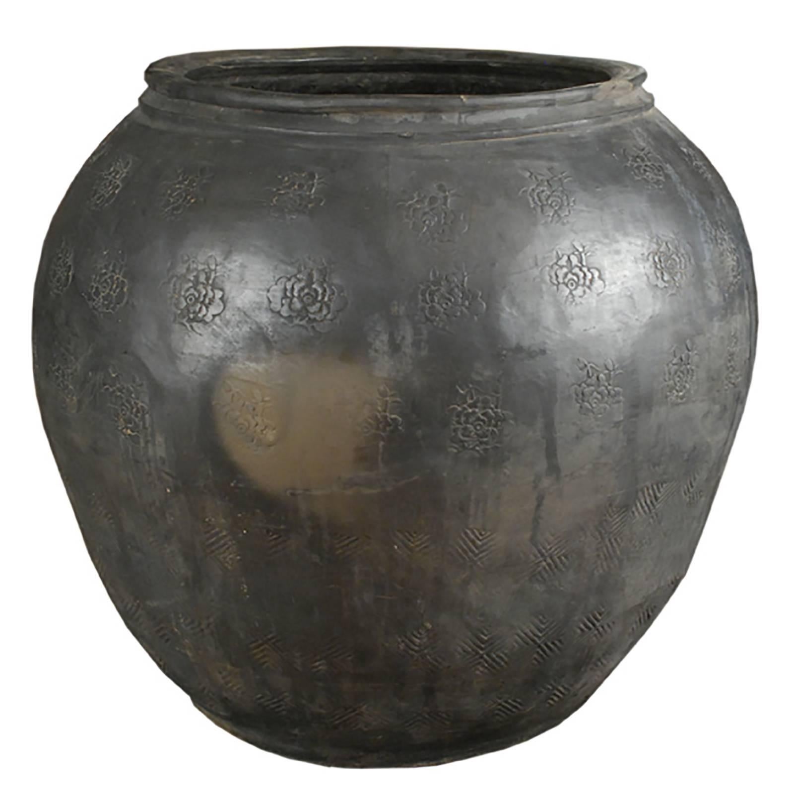 Artisans in the Shanxi region of China handcrafted this unique jar over a century ago. It is stamped with an irregular floral pattern. The matte black clay is characteristic of processes perfected by many generations of ceramicists working at