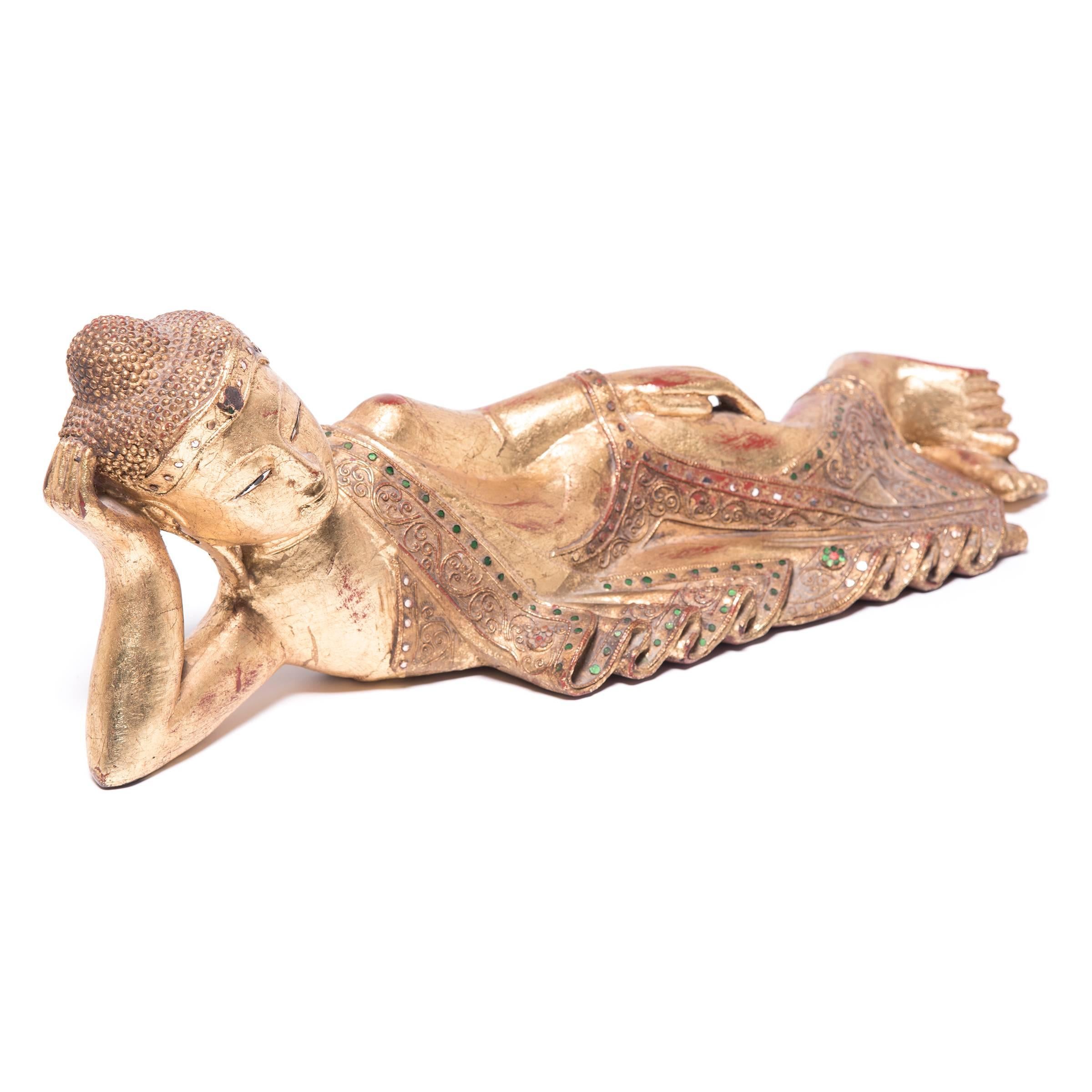 This gilded wood figure depicts Buddha in a reclining position. The posture is that of Nirvana Buddha, when the historical Buddha experiences his last moments on earth prior to entering nirvana and thereby breaking the cycle of birth, death and