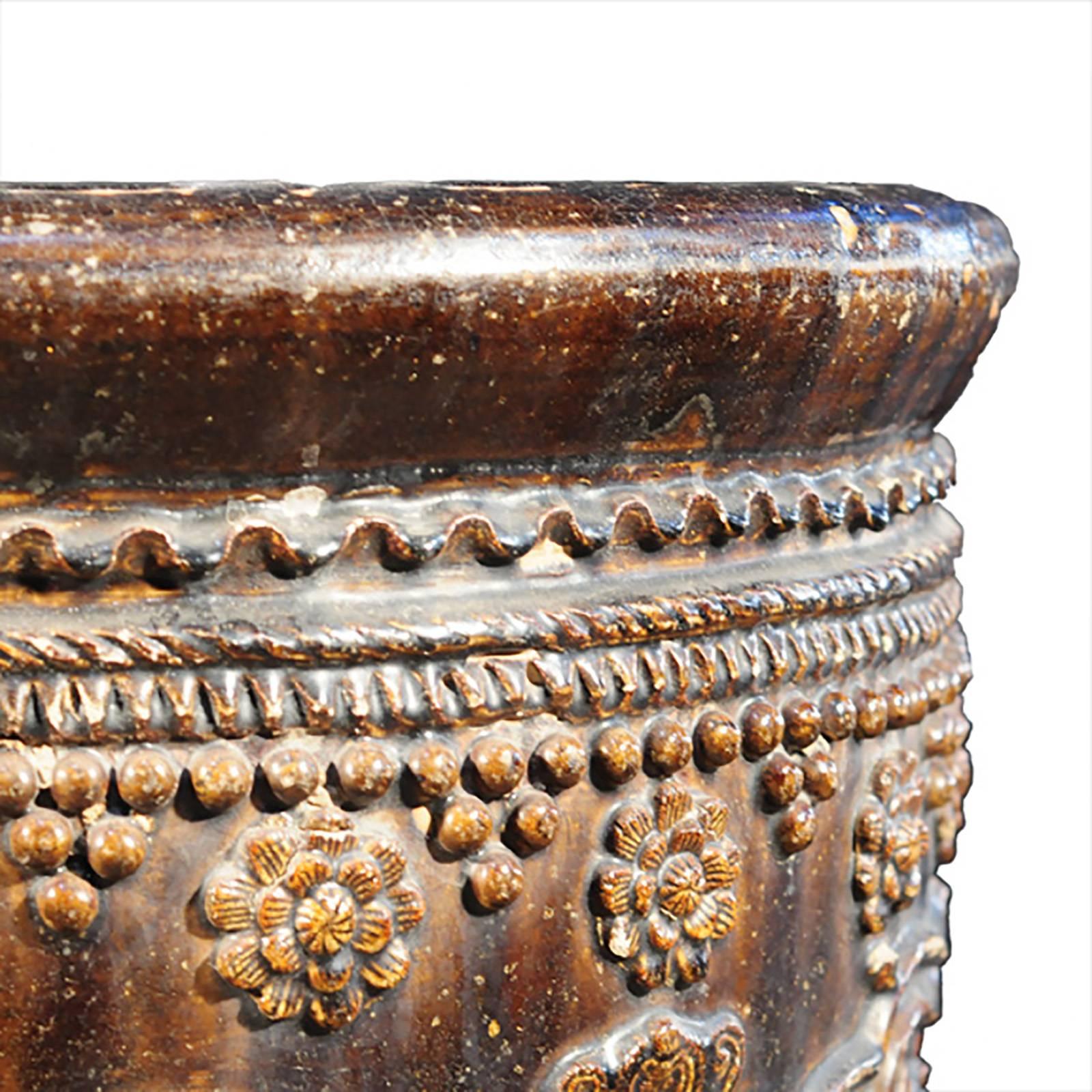 This unique glazed jar was handcrafted in northern China over a century ago, during the Qing Dynasty. It is decorated with stunningly detailed relief designs, the flowers have individualized petals, the cherry blossom branches are finely textured