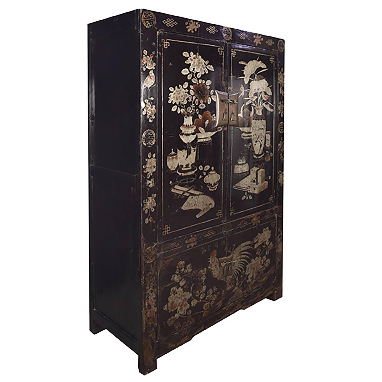 Featuring a rooster on its lower doors, this extravagantly decorated 19th century cabinet was likely commissioned at the time by someone born in the year of the rooster. Standing out against the cabinet’s richly lacquered black surface, the profuse