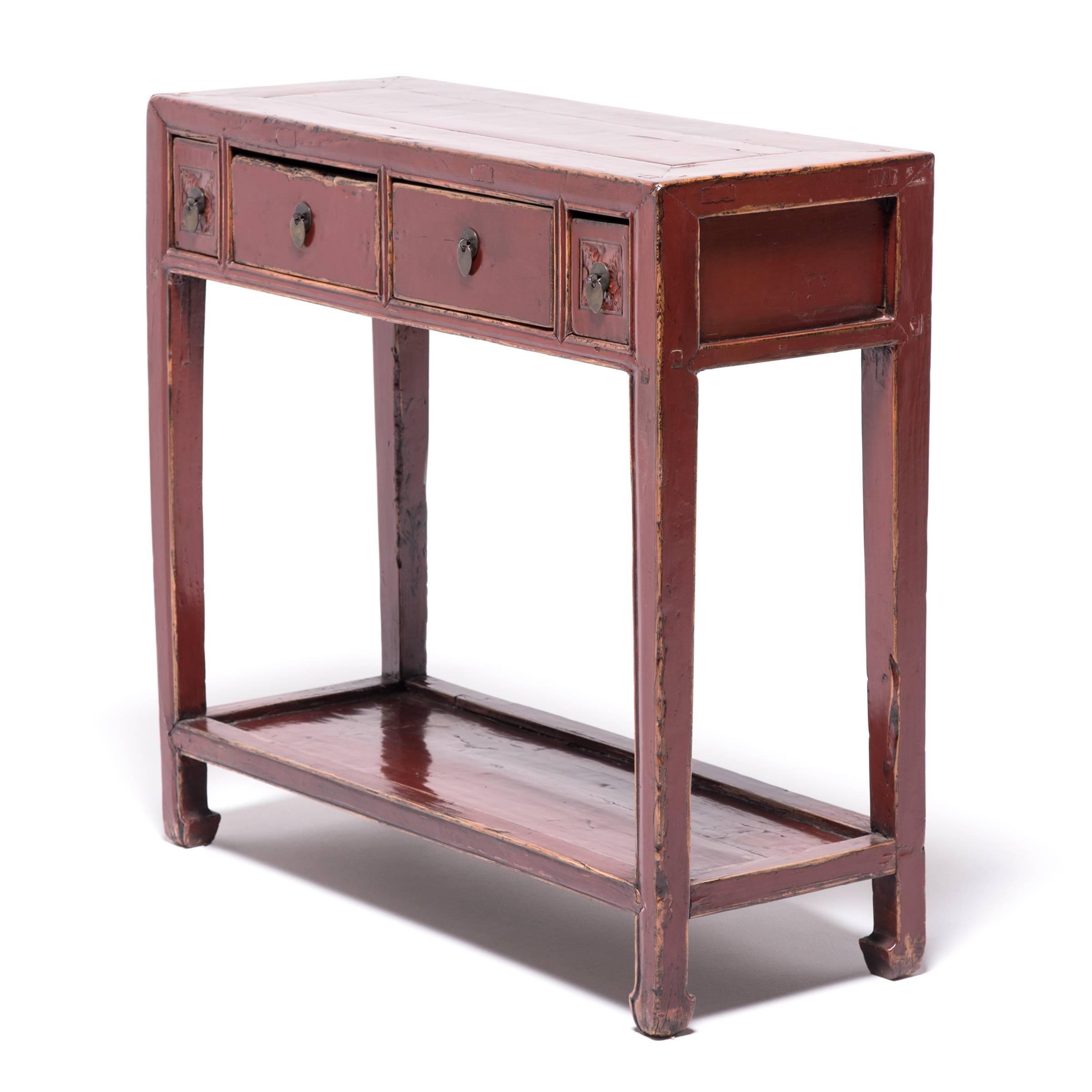 Brushed with many coats of red lacquer, this petite table once bore ritual objects as an altar table. Made around 1900 of Chinese northern elmwood, the table has a simple square shape, ever so slightly decorated with the subtle hoof-shaped feet,