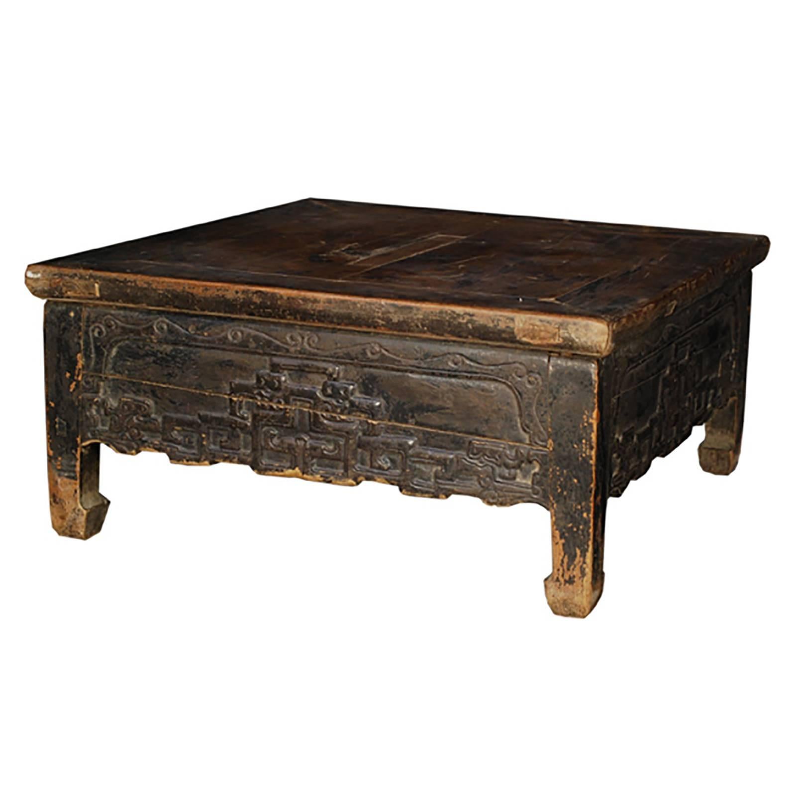 With its rustic, well-worn appearance, this low kang table has enjoyed decades of use as a platform for resting and socializing. Made of black-lacquered elmwood, the table showcases a delightful carved crooked dragon design on the apron and sturdy