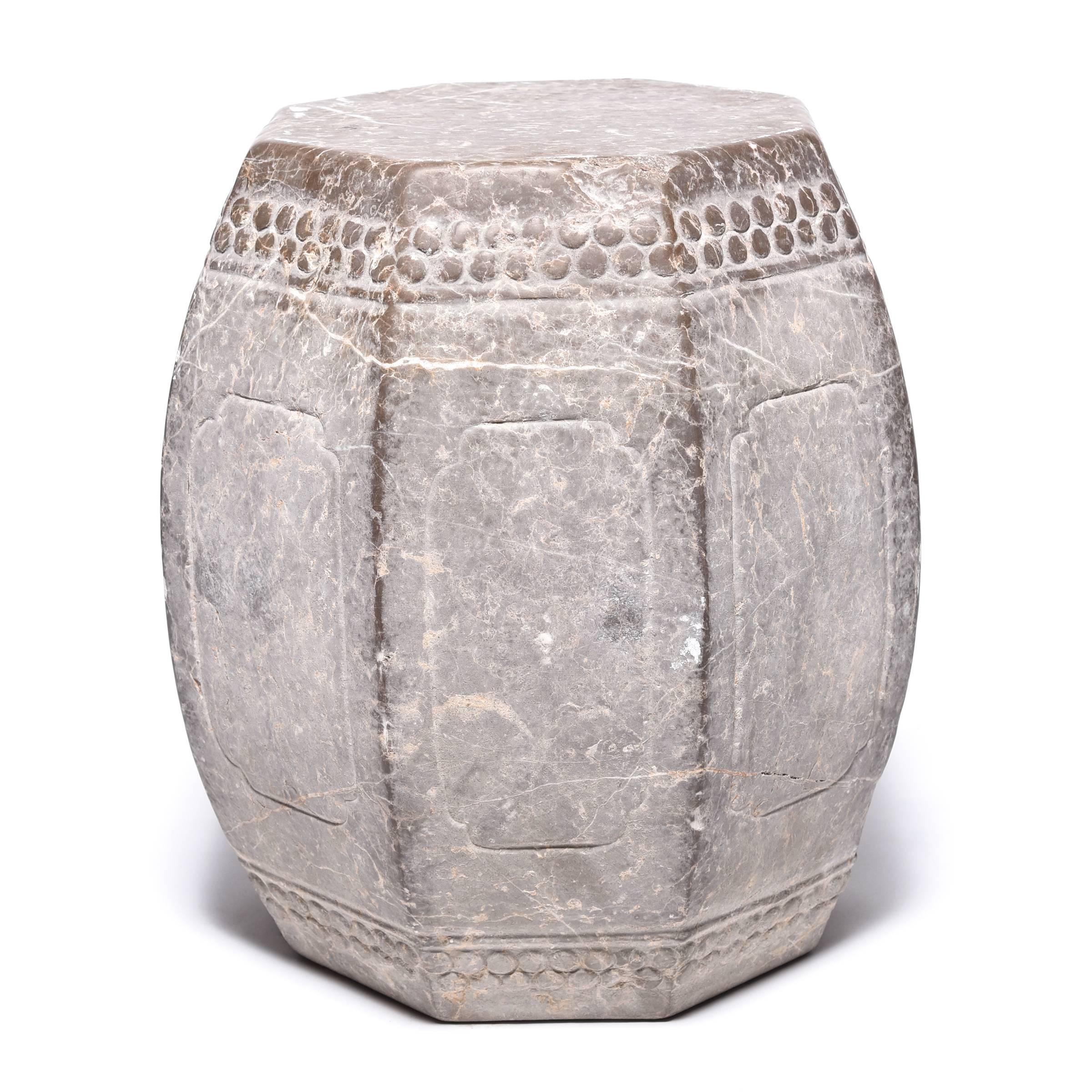 Hand-carved from a block of limestone, this carefully crafted eight-sided stool emulates the look of a drum. A pattern of boss-head nails around the top and bottom imitates those used to stretch a skin on an actual drum. Targeted polishing enhances