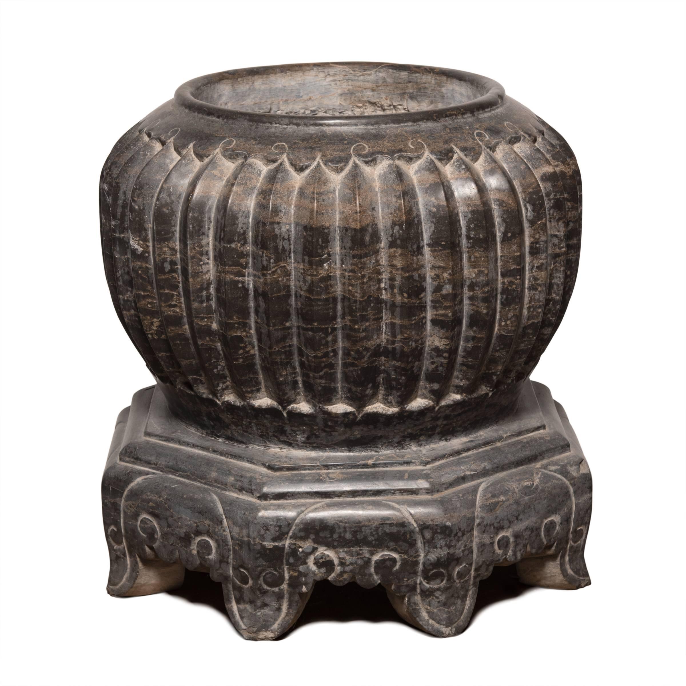 Carved from a solid block of dark marble, this melon form basin offers a significant sculptural presence. The raised pleats stand in for a melon’s ribs and diminish in height as they run down to the masterfully footed base. A traditional symbol of