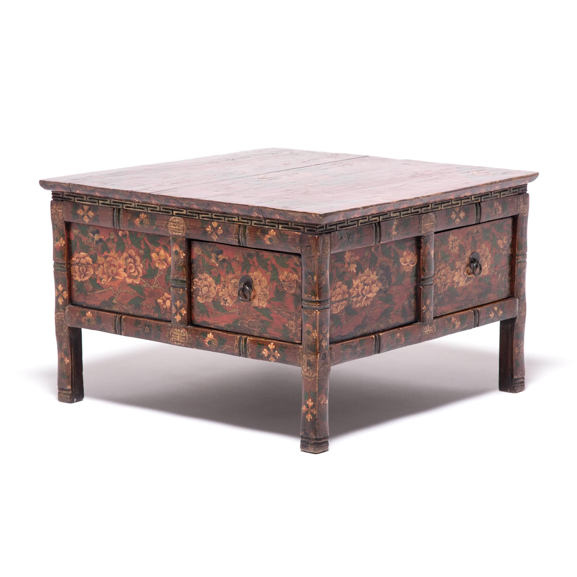 This extraordinary low Tibetan table dates to the mid-19th century and is lavishly decorated from end to end with tree peonies and offering fruits. The square table has a waisted design with corner legs and eight side panels, four of which have been