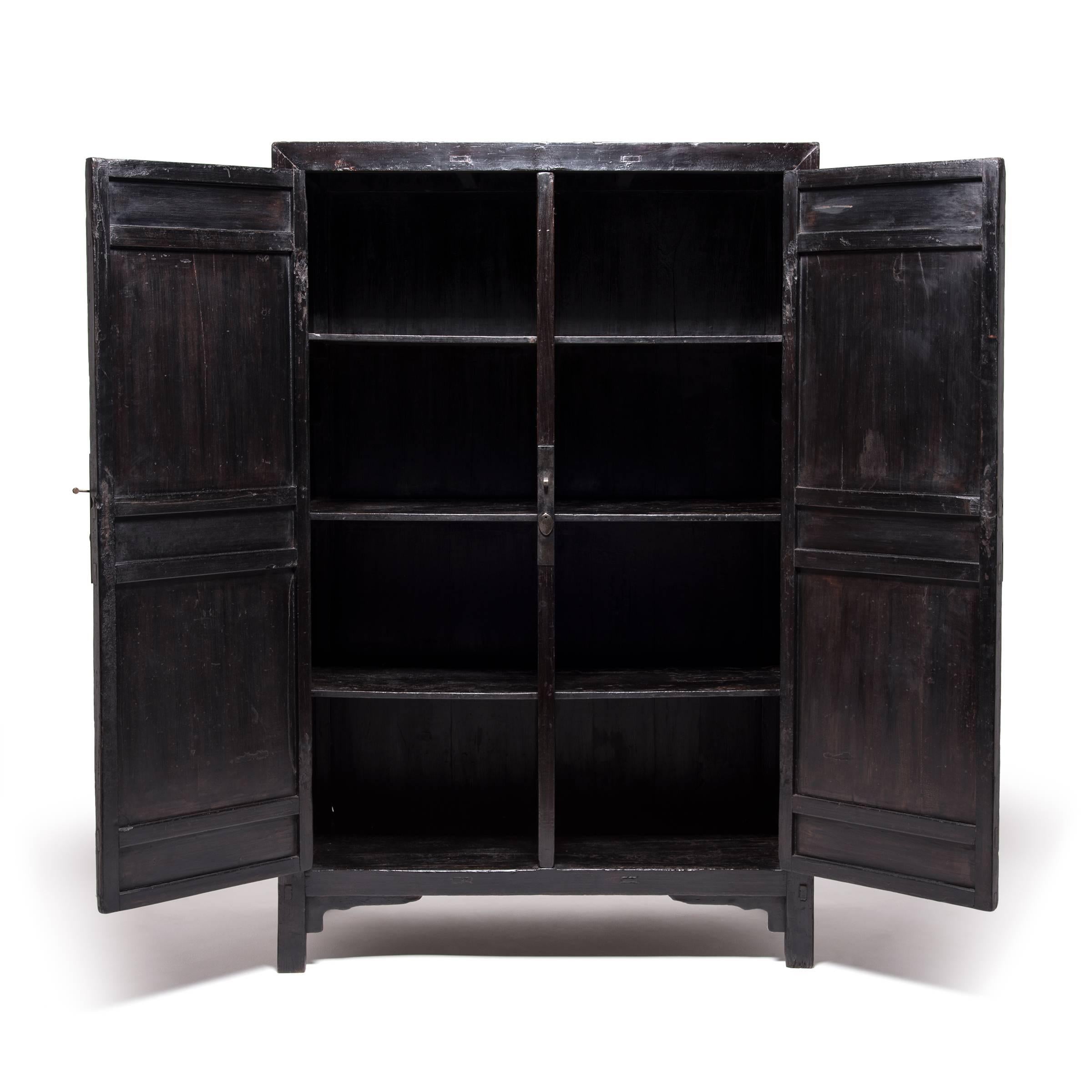 The imposing doors of this 19th century cabinet are accented with a trio of lozenge-shaped moldings that enliven the tall, rectilinear silhouette with horizontal lines. Invigorating the cabinet with a sense of rhythm and geometric tension, this