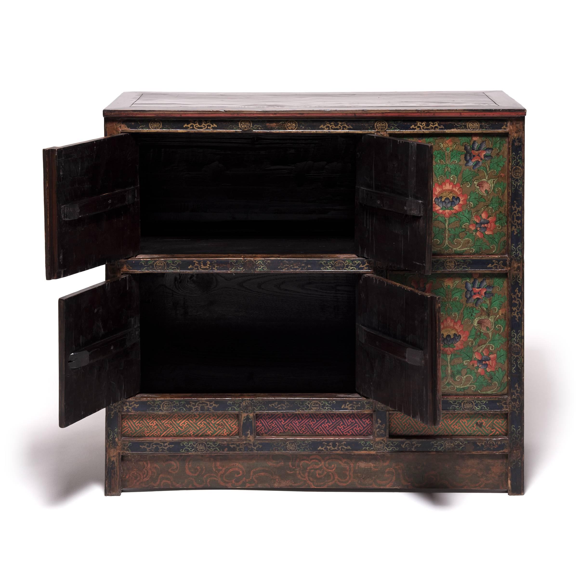 Made in 19th century Tibet, this extraordinary cabinet is lavishly decorated from end to end with beautifully painted floral motifs. Paneled doors depict a repeated motif of intricate, stylized lotuses, still vividly colored after a century of use.