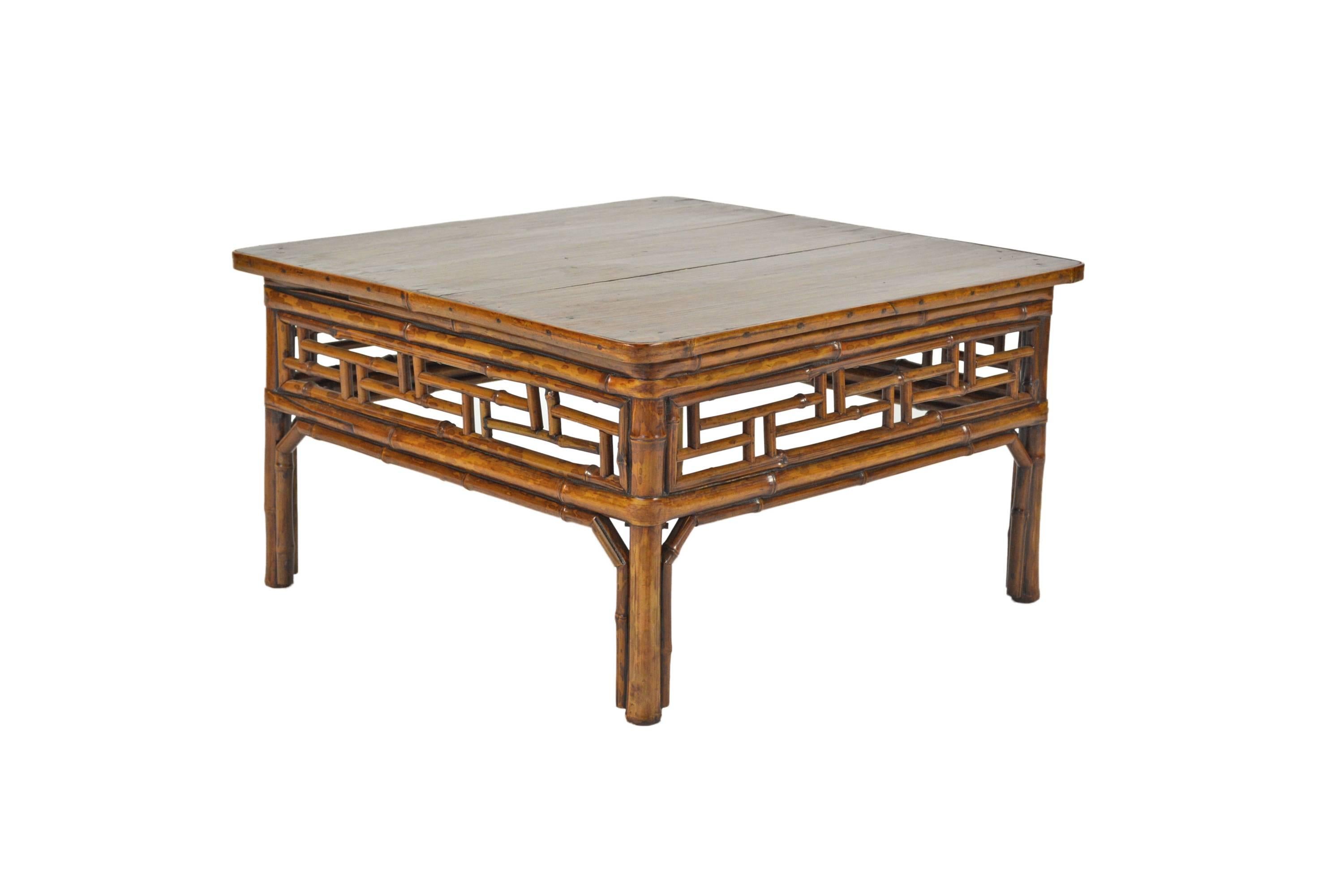 This late 19th century low square table from Southern China is built from spotted bamboo. It is brilliantly constructed with a geometric fretwork apron and legs held in place with double wraparound stretchers. Creating furniture from bamboo was a