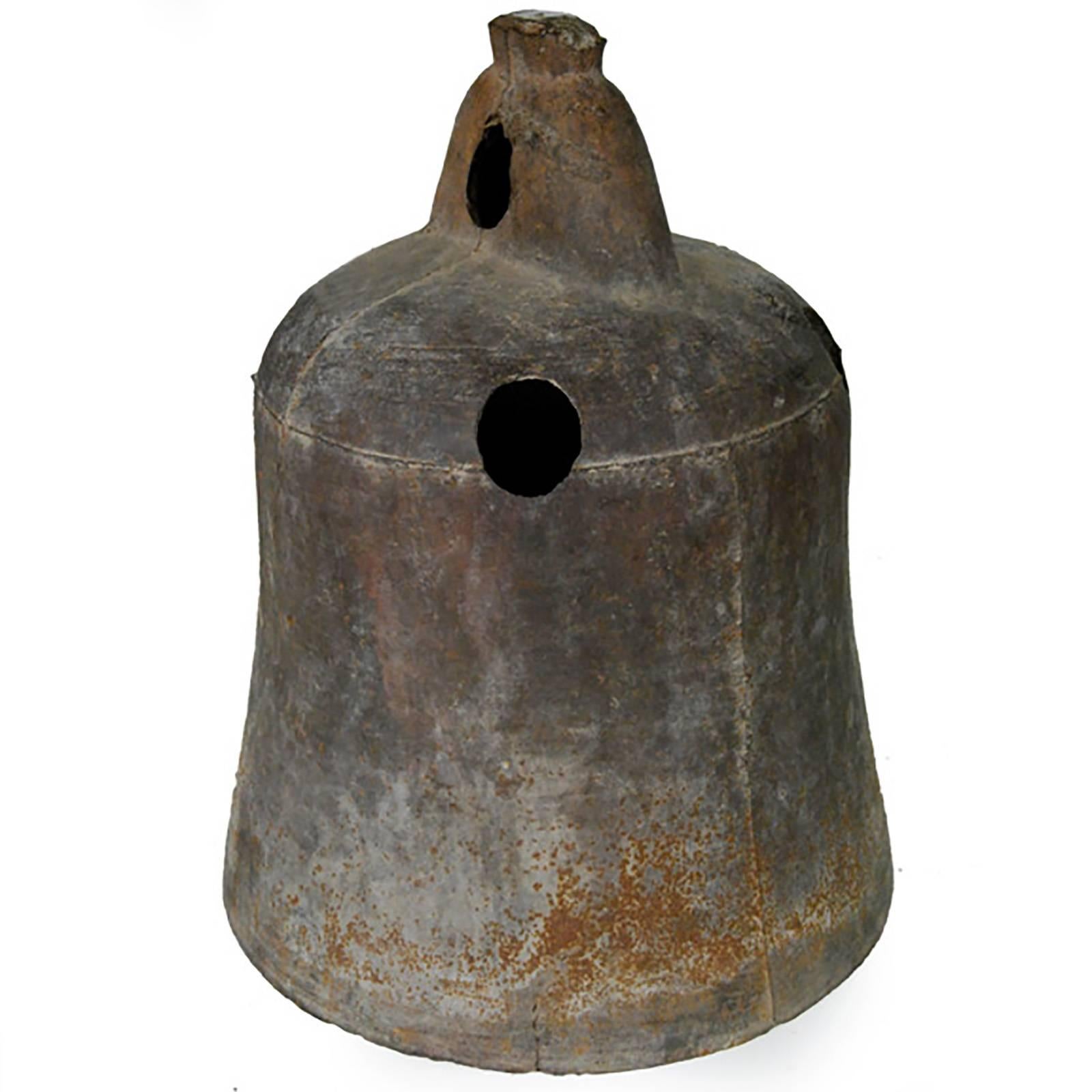 This rustic, 19th-century iron bell once pealed in celebration or gave notice of important events in a town in northern China. Marked with holes to affix the clapper or insert a pole, the bell looks lovely lit from within by a flickering candle or