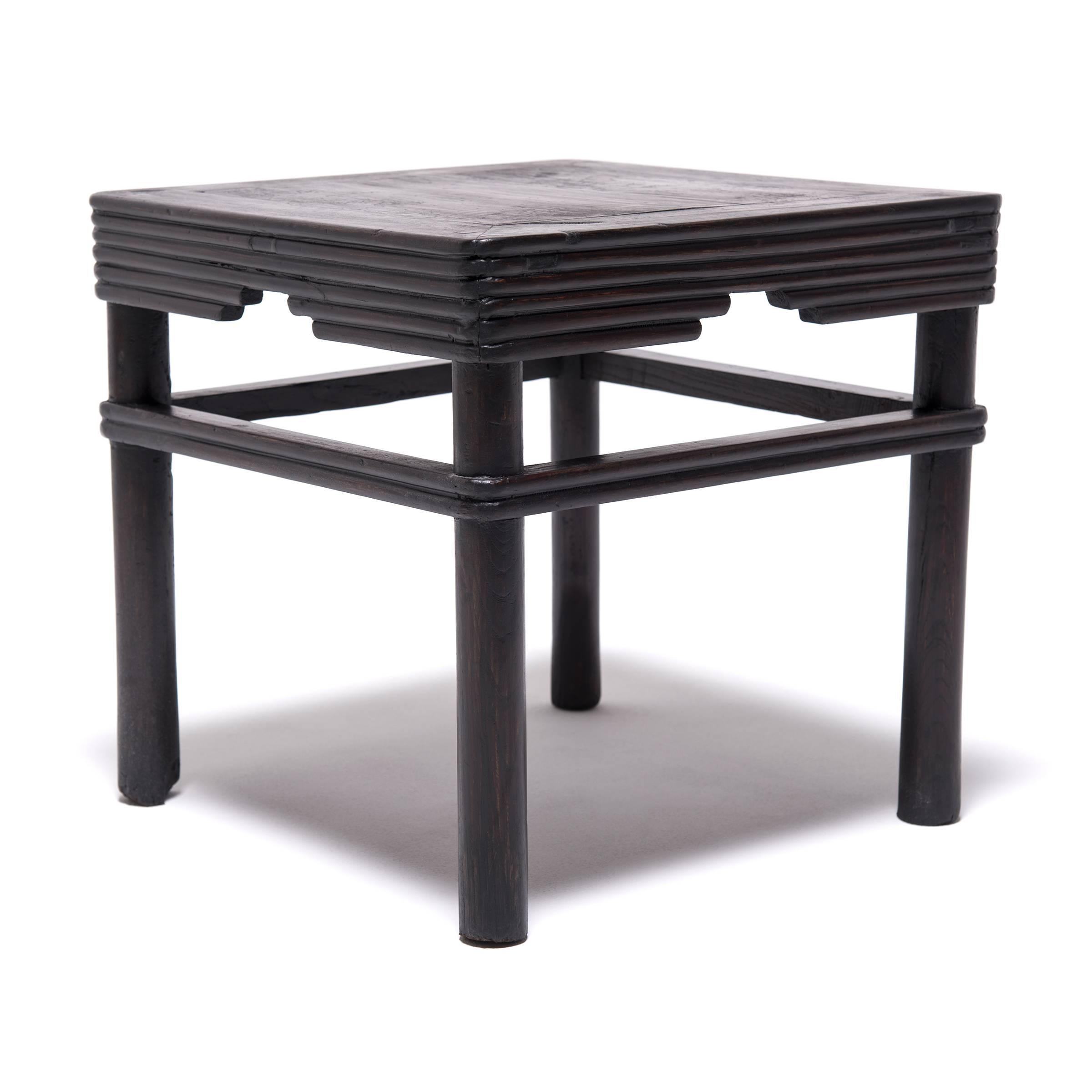 Paying tribute to the humble virtues of bamboo, ribbed woodwork wraps the legs and creates a stepped apron for this square stool, known as a fang deng. Expertly crafted from elm foraged from the forests of northern China, this stool was made in the
