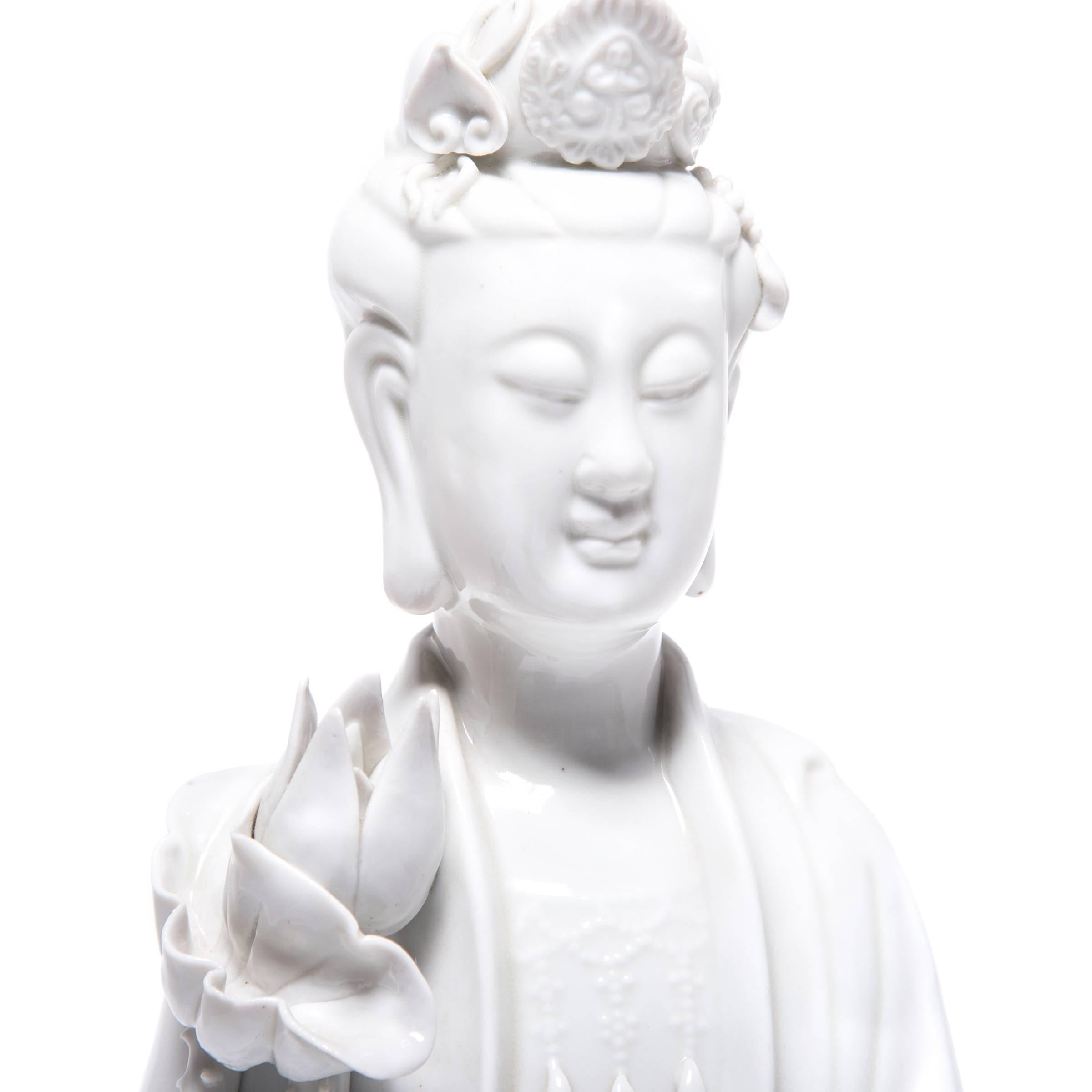 A symbol of compassion and wisdom, Guanyin is a bodhisattva venerated by Buddhists and Taoists alike. This exquisite porcelain sculpture from the early 20th century depicts the serene-faced goddess holding lotus plants, symbols of purity and