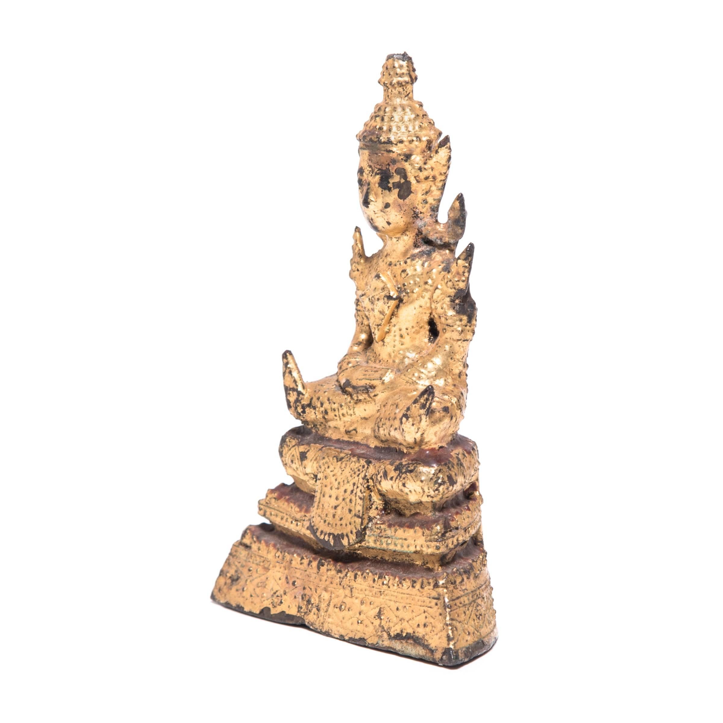 This petite Thai Buddha is a gallery favorite. With legs crossed and his hands in a meditative gesture known as a mudra, the Buddha is depicted in a transcendental state of meditation. Currently displayed inside a lovely rootform shrine, the eye