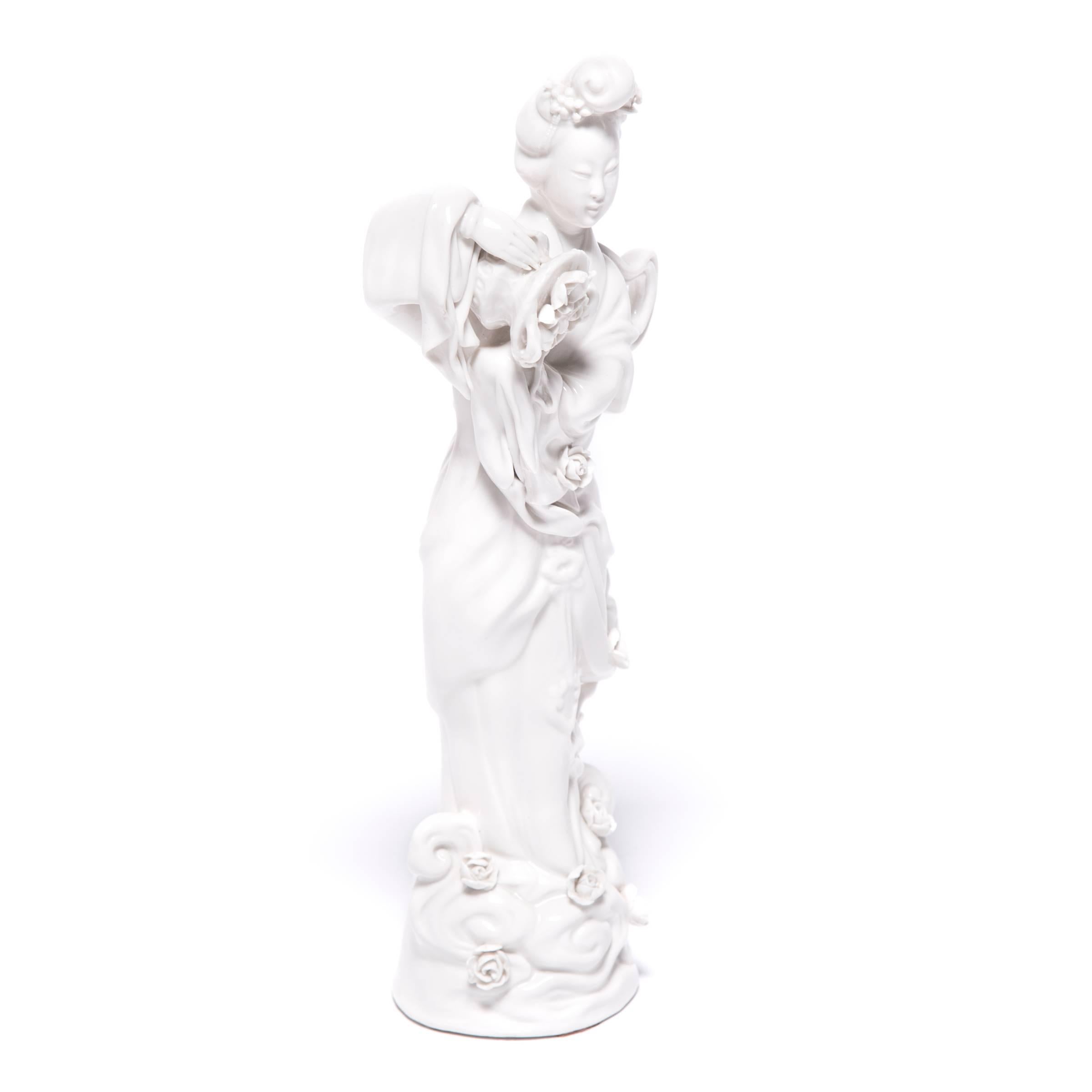 A symbol of compassion and wisdom, Guan Yin is a bodhisattva venerated by Buddhists and Taoists alike. This exquisite porcelain sculpture from circa 1900 depicts the serene-faced goddess spilling roses from a basket. The blossoms cascade down her