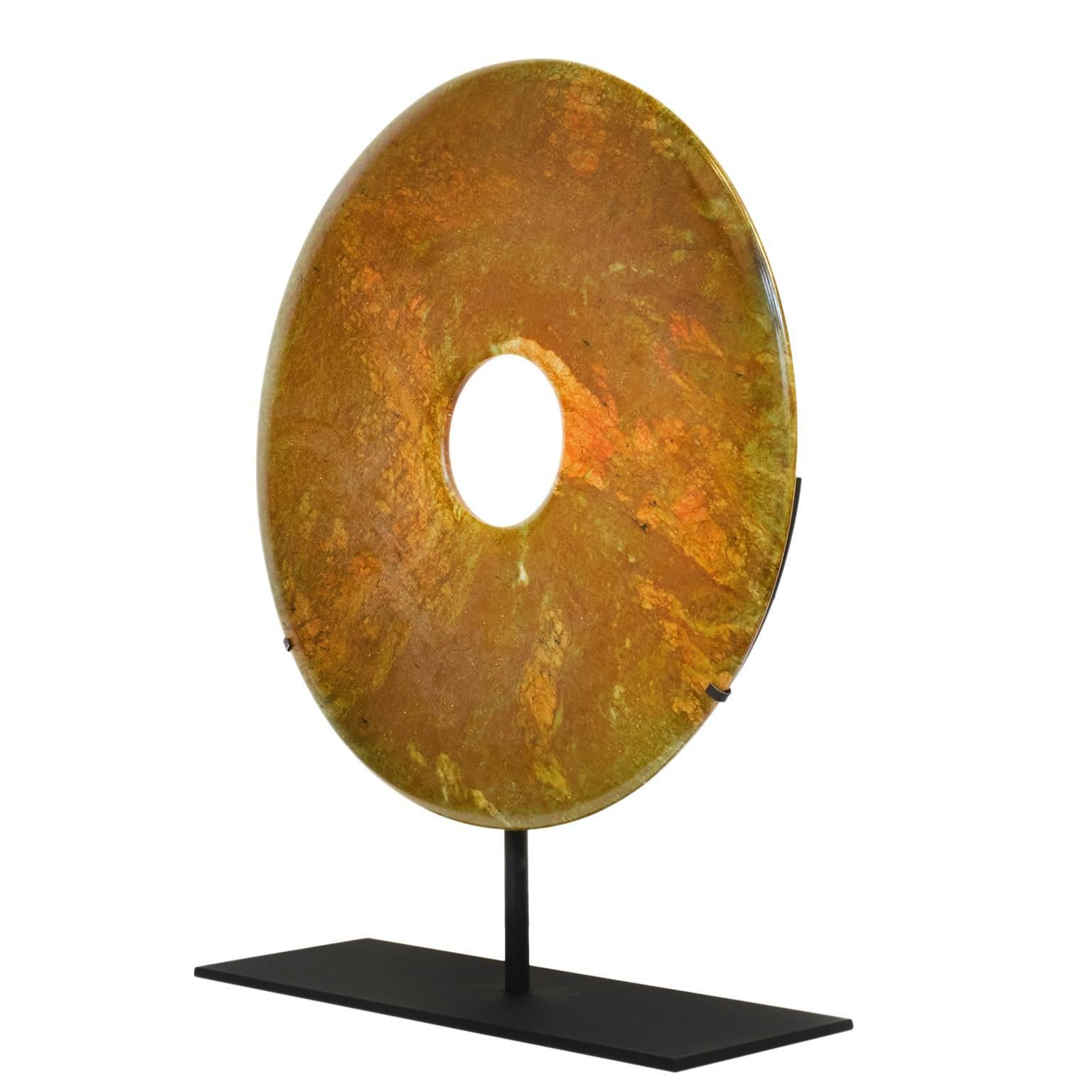 A beautiful orange carved stone Chinese Bi Disc, a symbol of heaven and wealth, mounted on a custom steel stand.