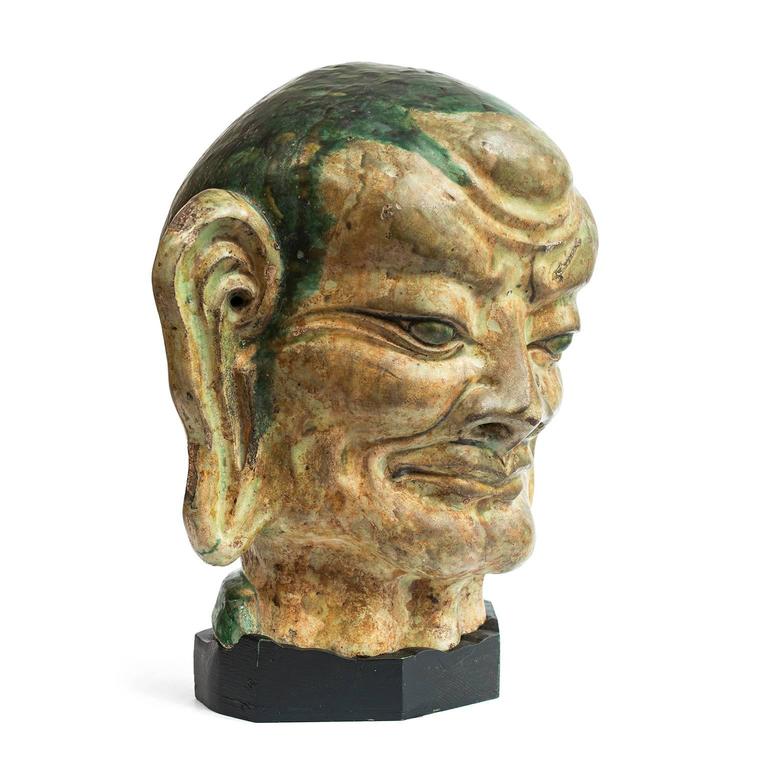 This imposing figure is the head of an Arhat, a Buddhist devotee who has attained enlightenment, also called a “Luohan.” The eighteen original Arhat are the personal disciples of Buddha and the guardians of Buddhist adherents. Each is represented