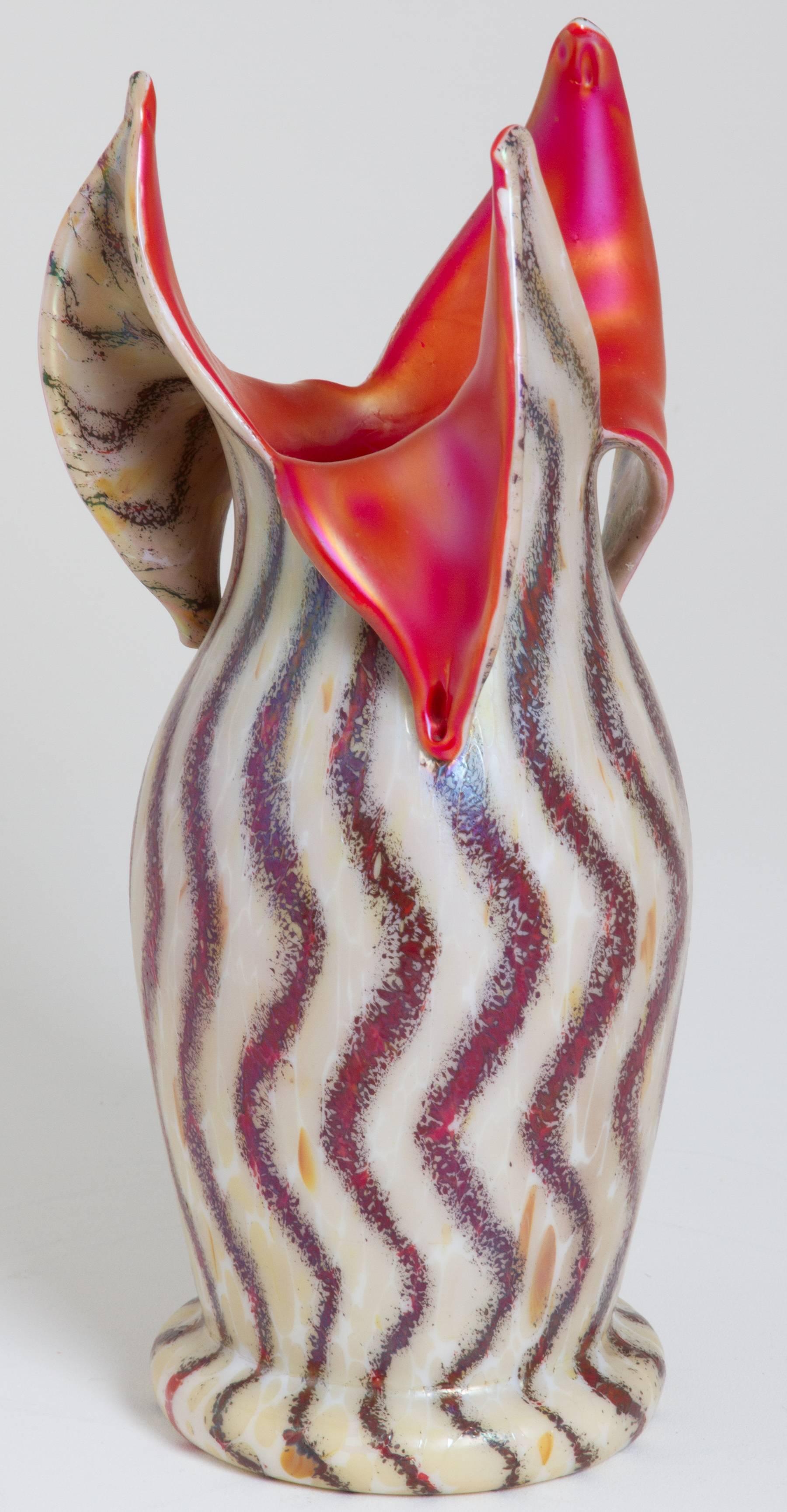 This is a striking Czech vase, having a fabulous iridescent golden orange interior and an optical striped exterior. The vase has a polished pontil and the lip of the vase is open like three petals. It looks like it is on fire when in the light.