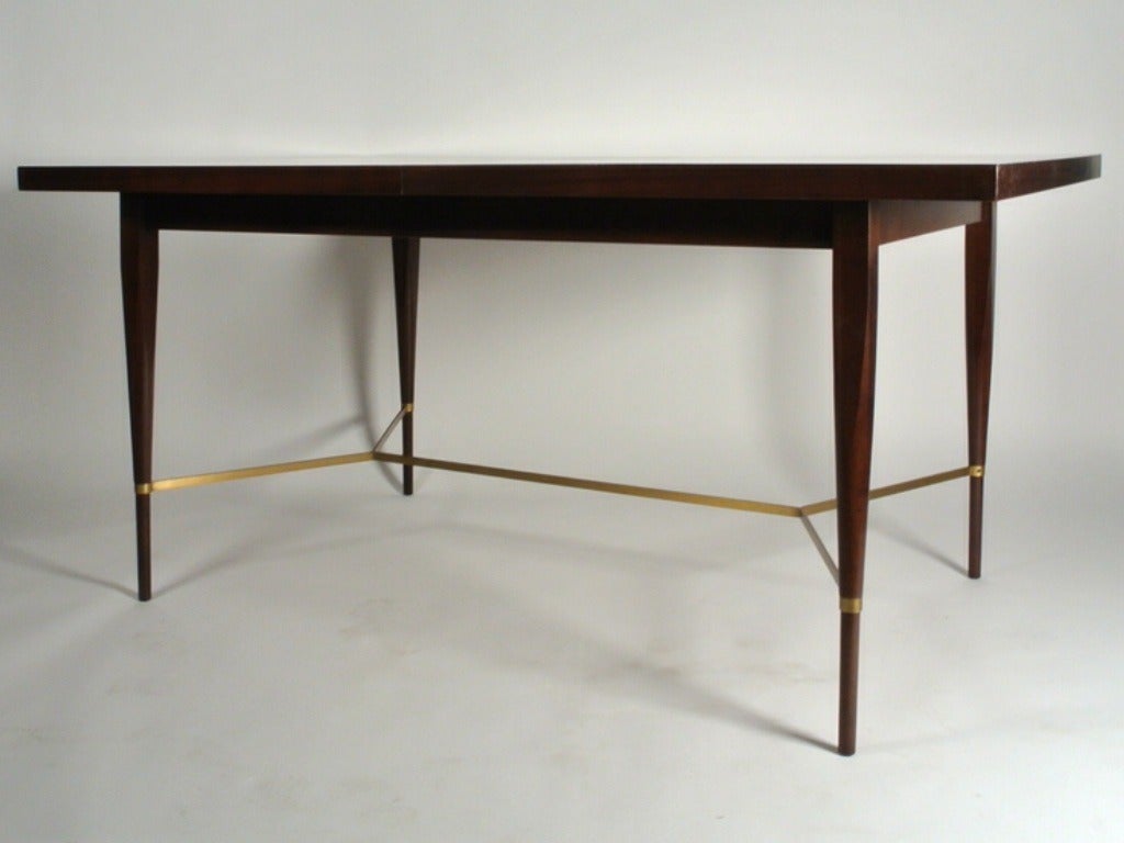 Esstisch aus philippinischem Mahagoni mit X-Strecker aus Messing zwischen konischen Beinen, entworfen von Paul McCobb, Teil seiner Irwin-Kollektion für Calvin. Beinhaltet zwei 12