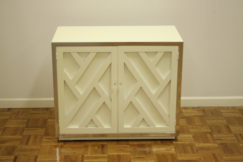 Pair of matching cabinets with chrome trim and doors with Chinese Chippendale style doors with Lucite pulls. Should be re-lacquer, stains to tops and minor scuffs to trim.