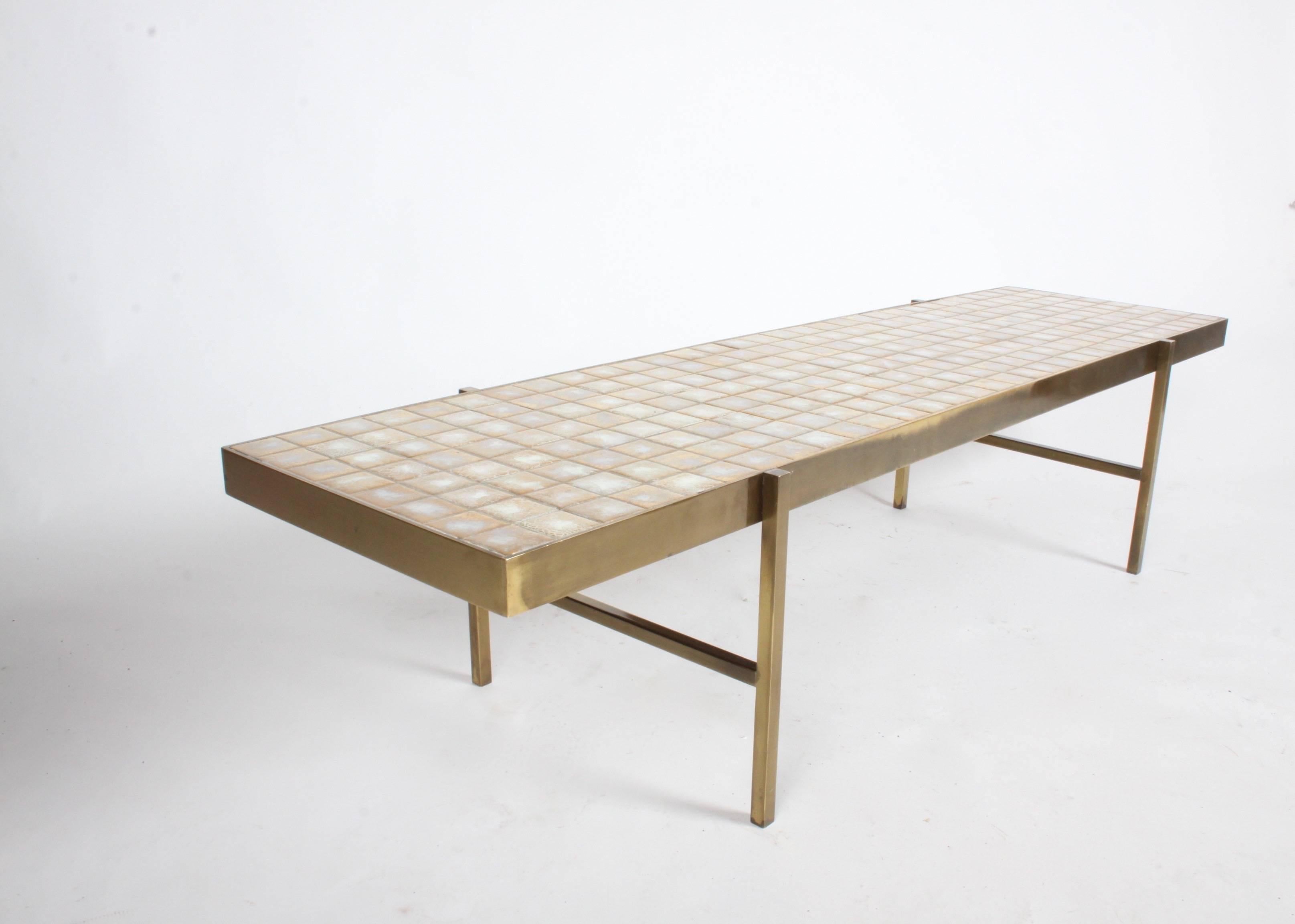 In the style of Edward Wormley for Dunbar, rectangular coffee table with Natzler like crazed gold and white tiles. Nice scale to solid brass frame and legs, very heavy table! Overall great condition, with nice patina. Some minor loss to grout in