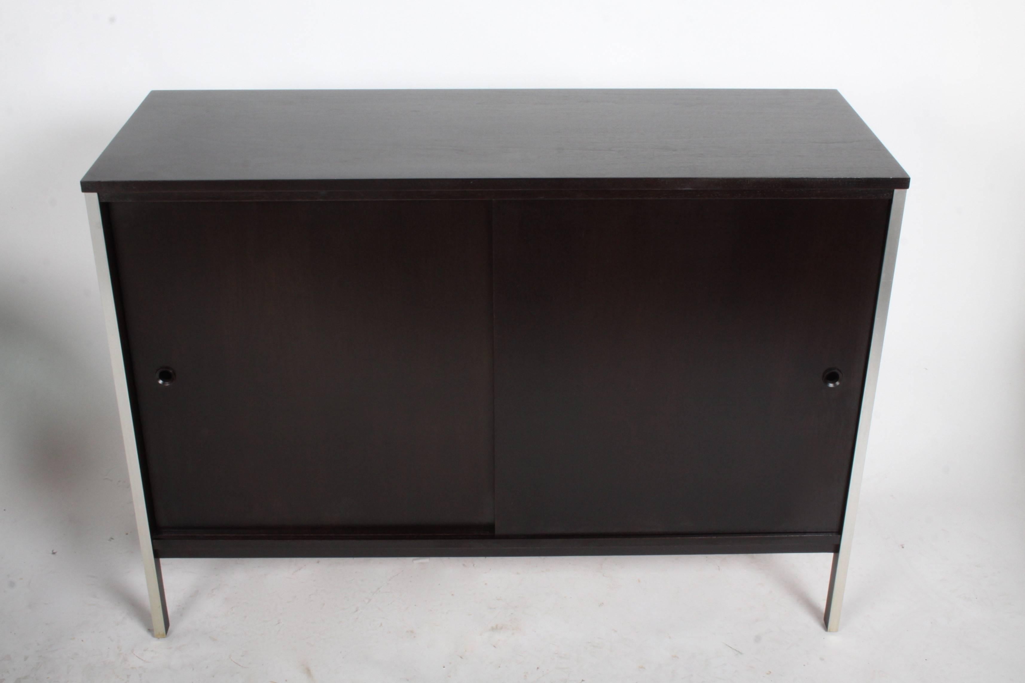 Pair of Paul McCobb for Calvin credenza refinished in dark espresso with sliding doors and aluminum trim. Each side has an adjustable shelf, shelf size is 23