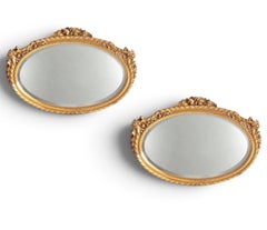 Coppia di specchi in legno dorato con stemmi intagliati con motivi floreali e fogliati decorati