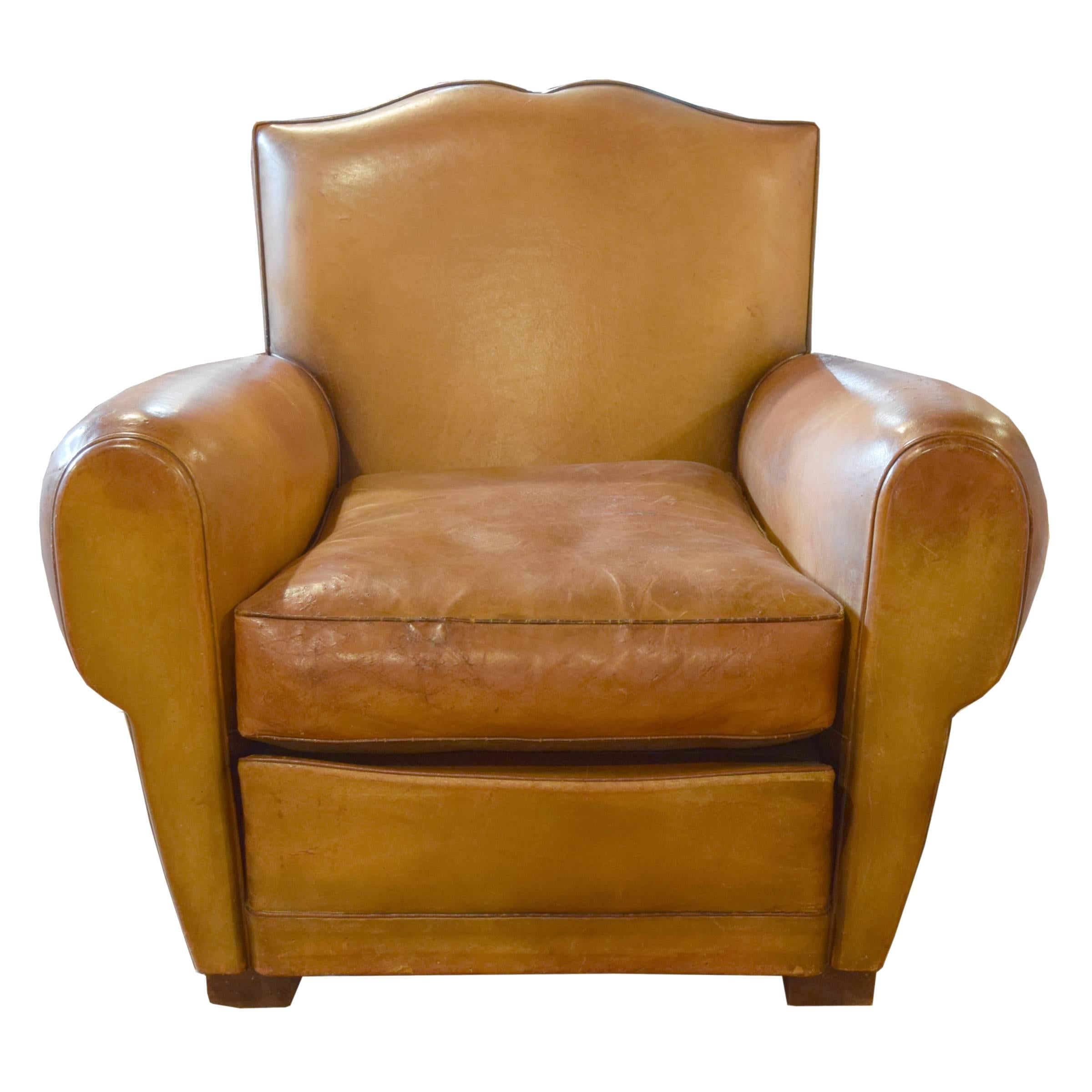 A pair of French leather club chairs with mustache form back, brass nail-head trim, and wooden feet, circa 1930.